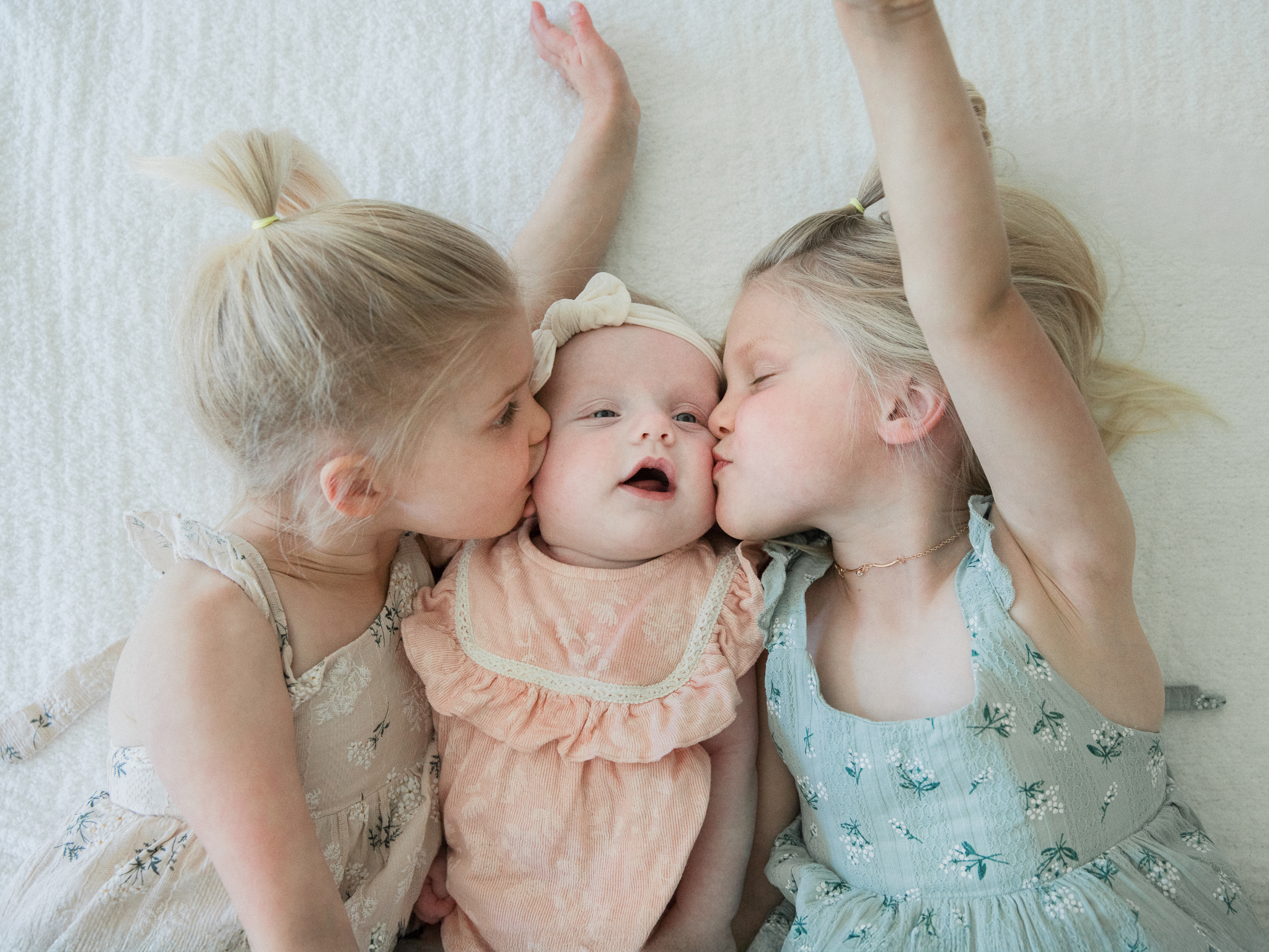 Big sisters kissing baby Lenny with love.