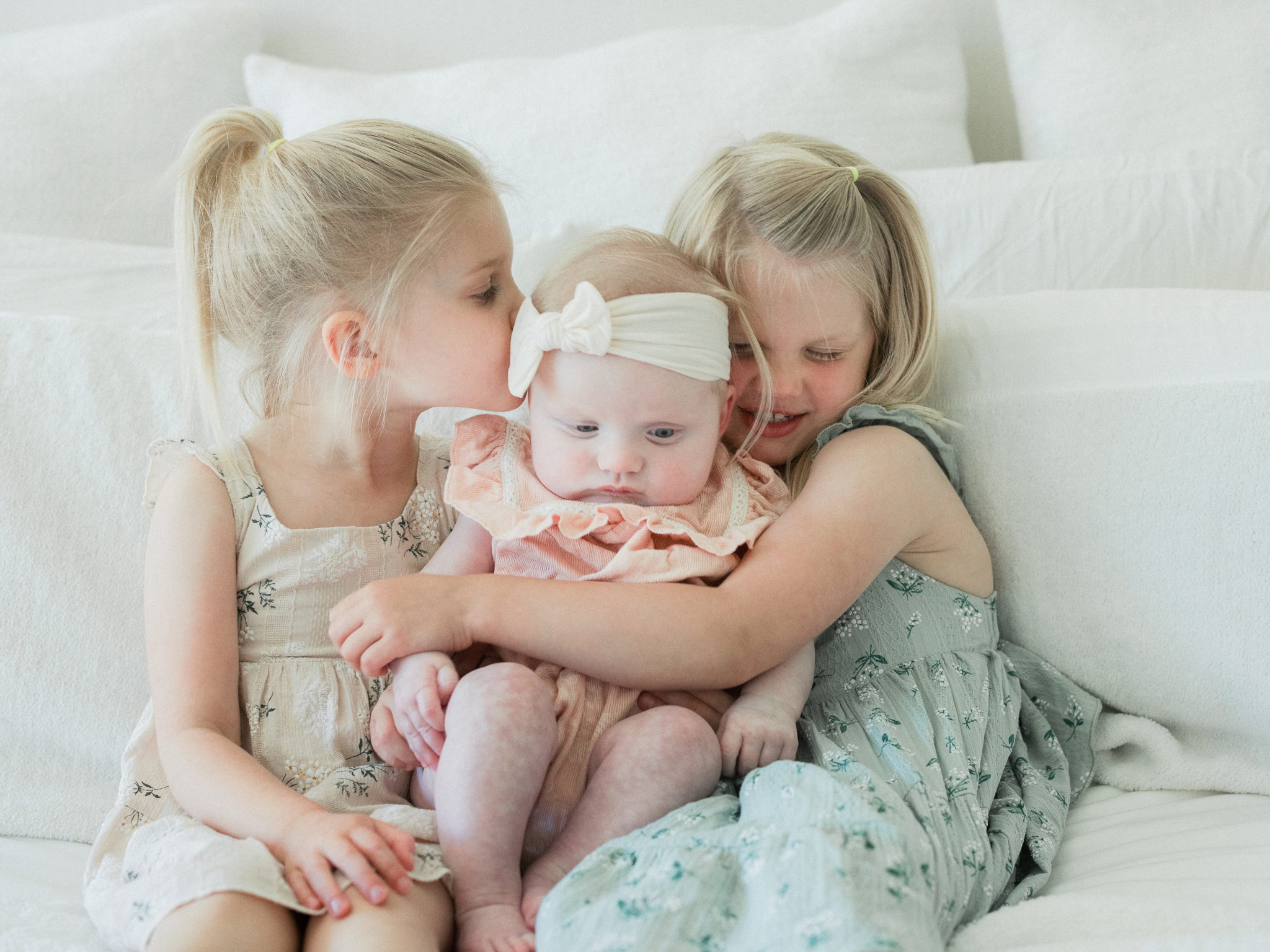Liv and Logan snuggling their baby sister during an in-home newborn photography session in Missouri by Love Tree Studios.