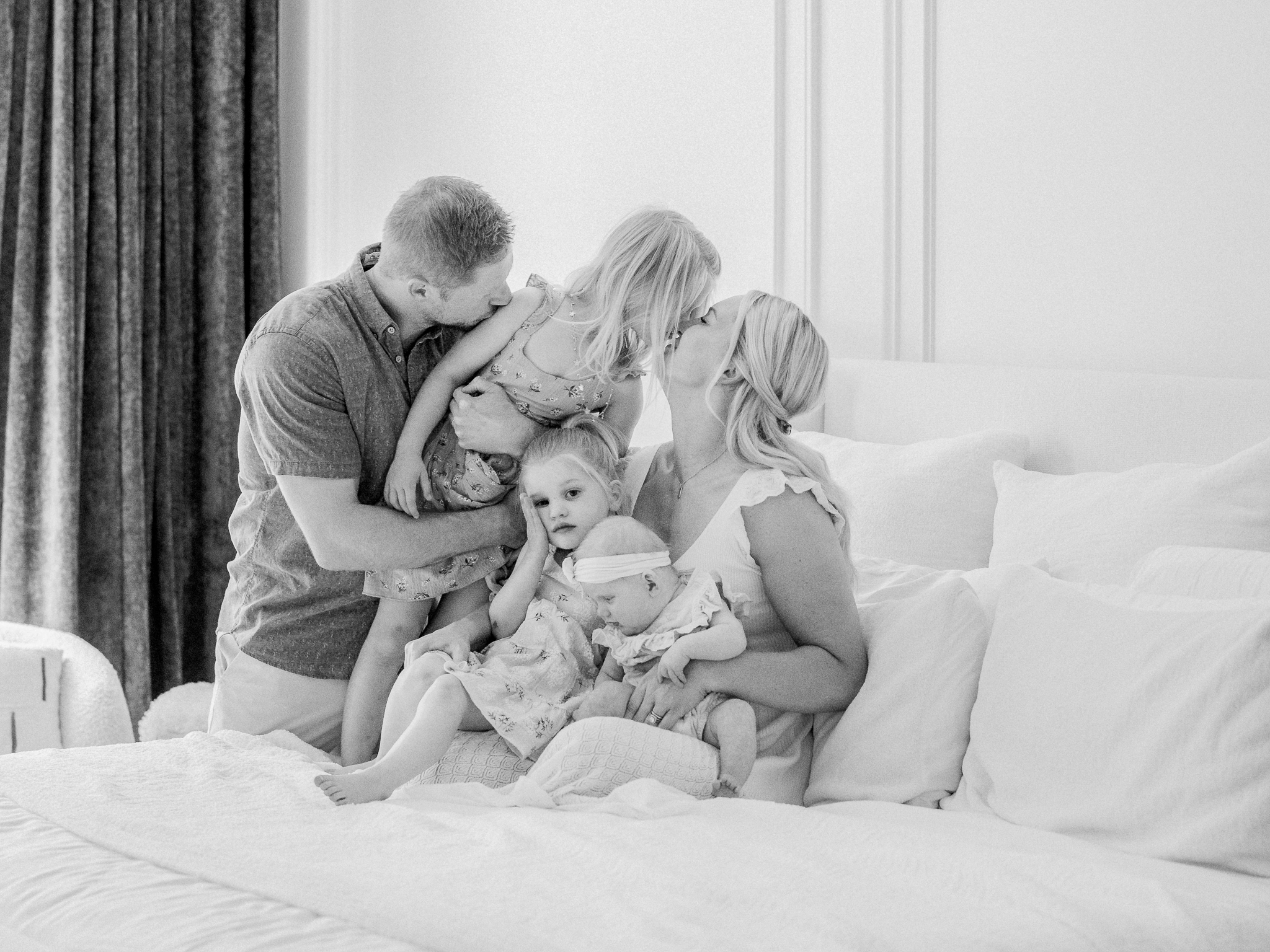 Family sharing kisses and love on the bed during a lifestyle newborn photography session in Missouri with Love Tree Studios.