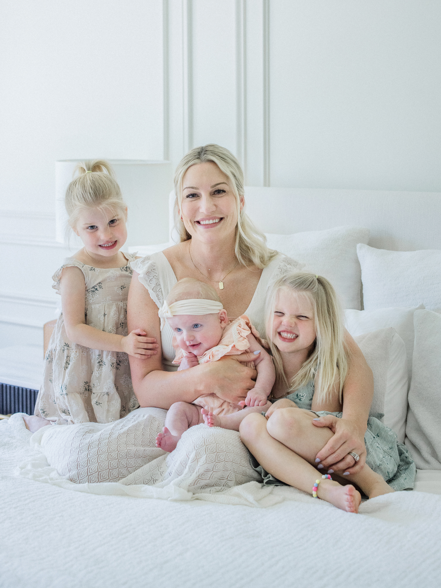 Mother smiling with her three daughters during a bright and joyful in-home newborn photography session in Missouri by Love Tree Studios.