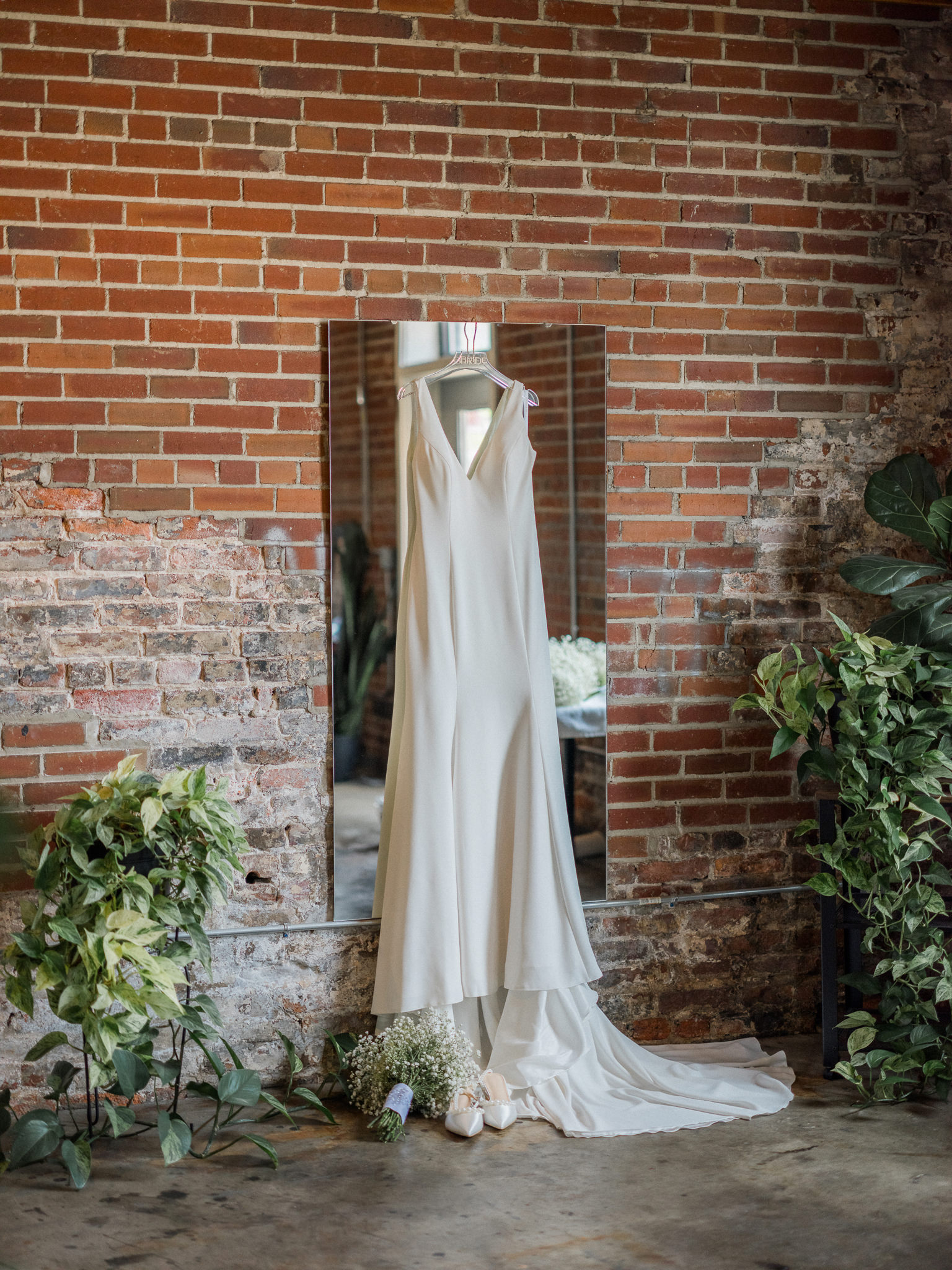 Bridal gown hanging against exposed brick wall captured by Love Tree Studios for Jefferson City wedding photography in Jefferson City, Missouri.