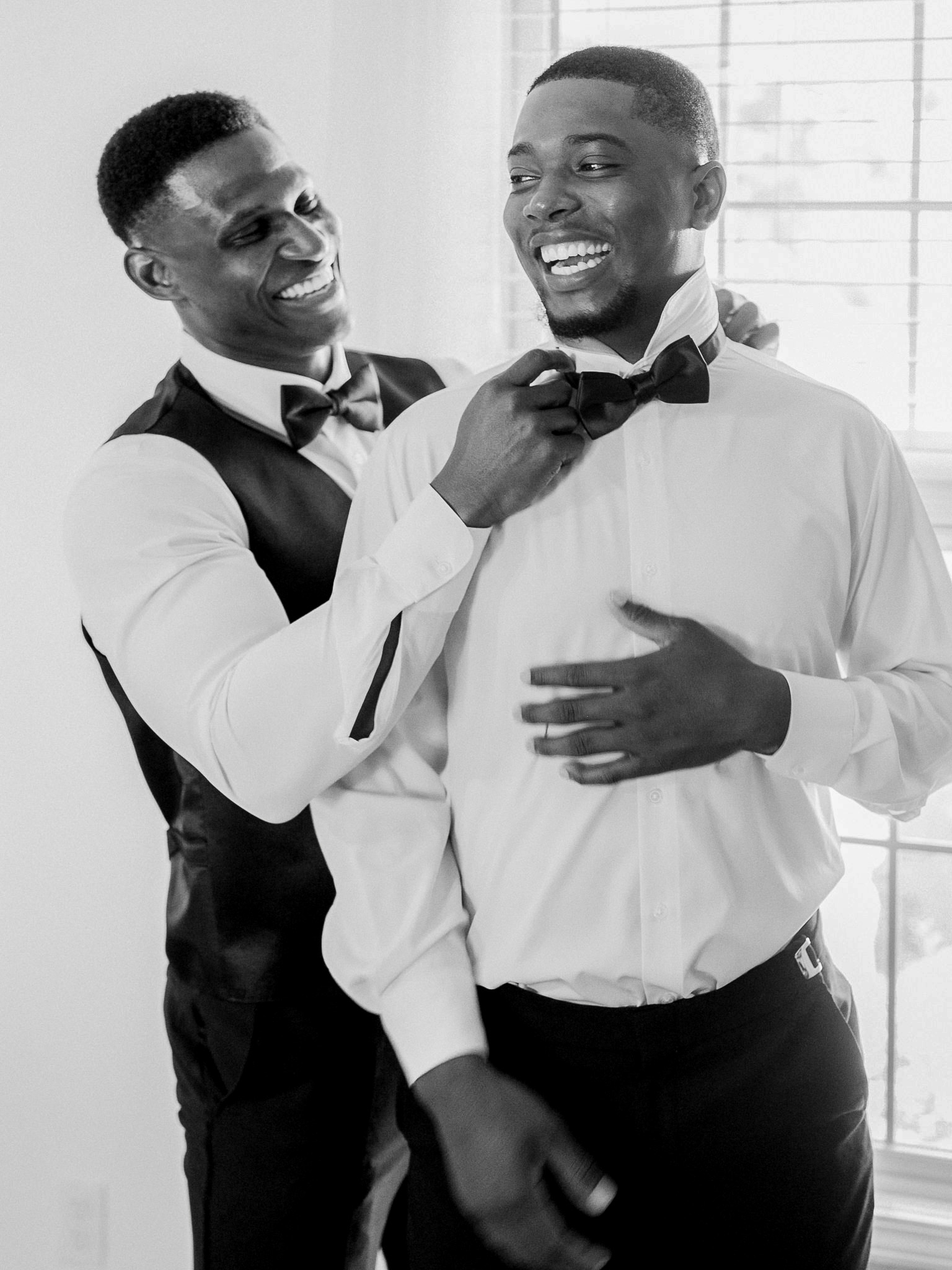 Groomsman adjusting groom's bow tie with care captured by Love Tree Studios for Jefferson City wedding photography in Jefferson City, Missouri.