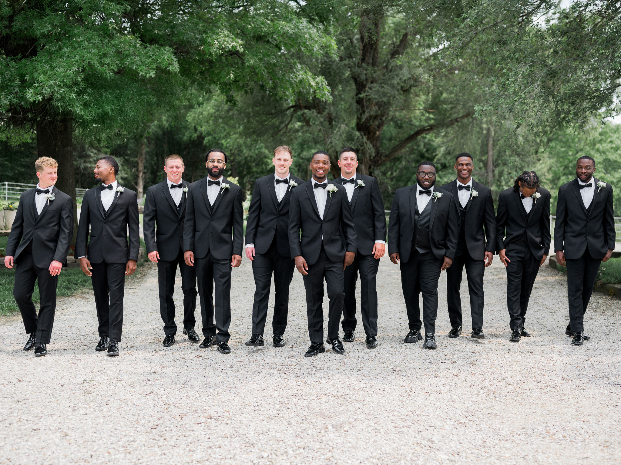 Groomsmen walking together outdoors in black tuxedos captured by Love Tree Studios for Jefferson City wedding photography in Jefferson City, Missouri.