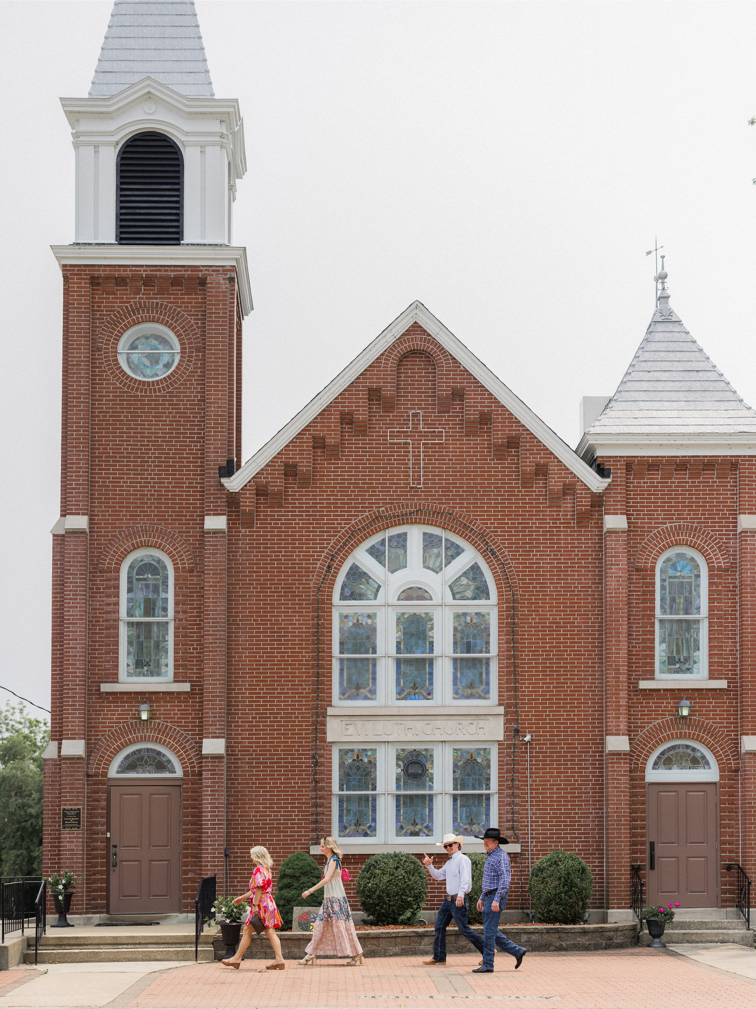 Guests arriving at red brick Trinity Lutheran Church in Russellville captured by Love Tree Studios for Jefferson City wedding photography in Jefferson City, Missouri.
