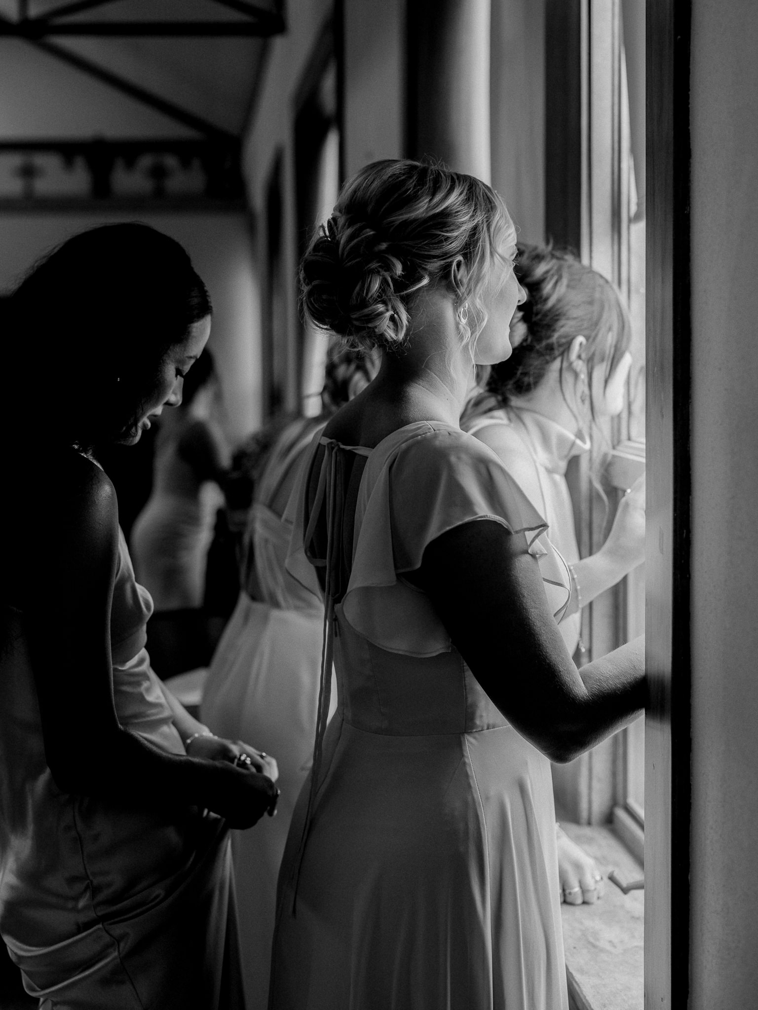 Bridesmaids peeking out the window moments before the ceremony captured by Love Tree Studios for Jefferson City wedding photography in Jefferson City, Missouri.