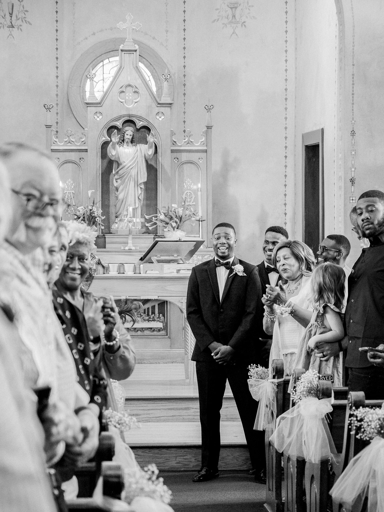 The groom stands smiling at the altar surrounded by guests in a historic Missouri church — captured by Missouri wedding photographer Love Tree Studios.