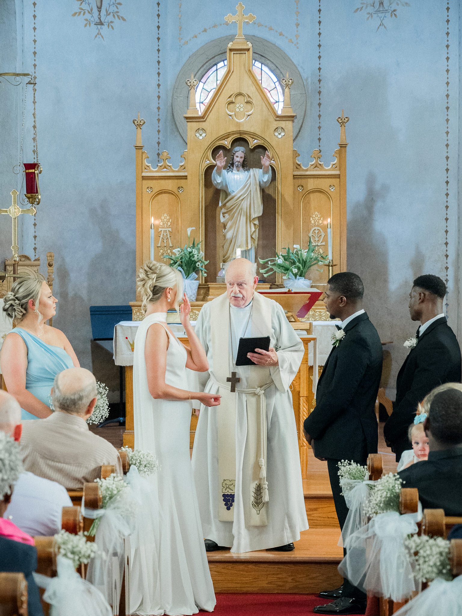 Bride and groom exchange vows in front of a priest during their traditional church ceremony — photo by Missouri wedding photographer Love Tree Studios.