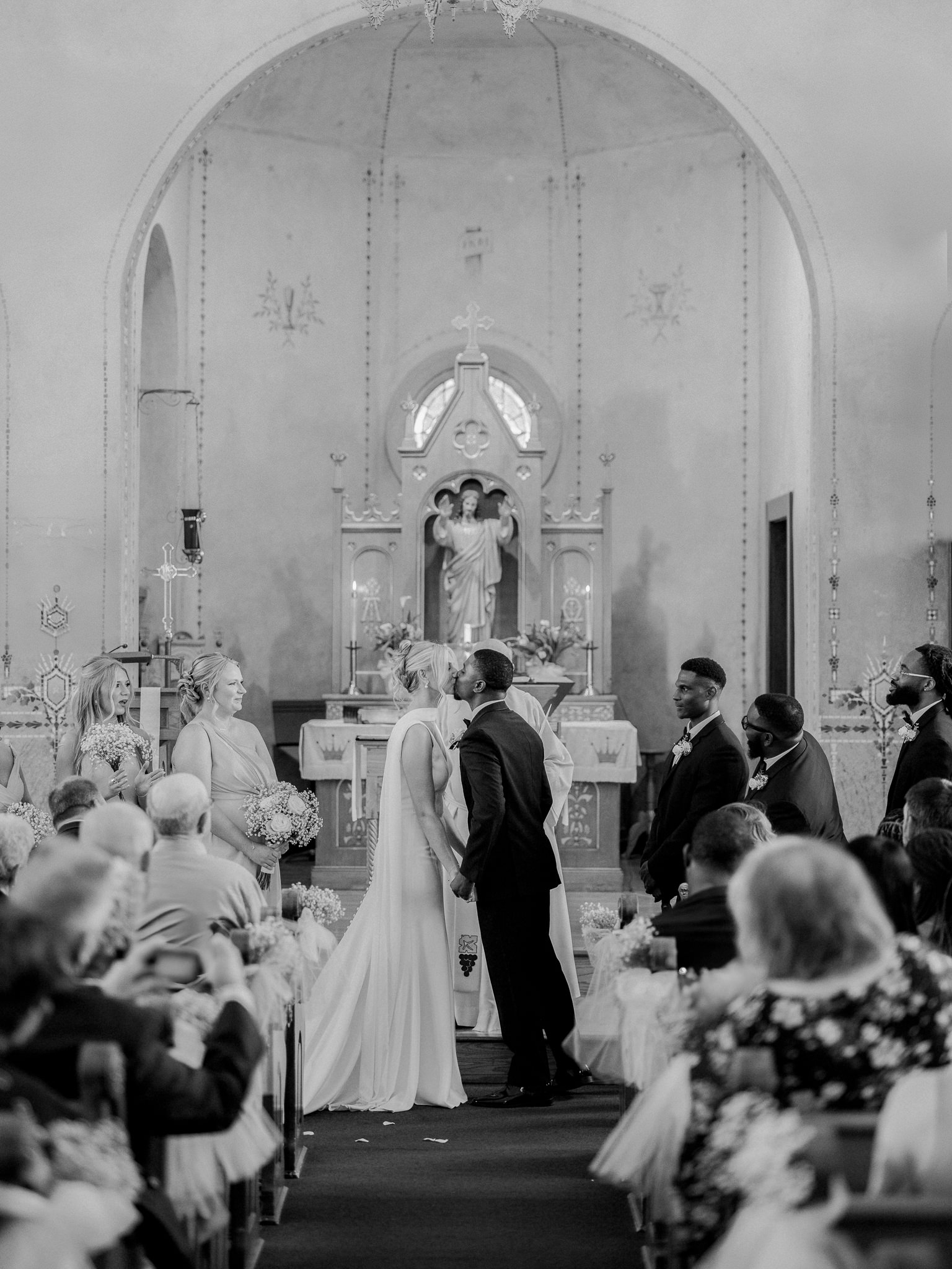 Black and white image of the couple sharing their first kiss at the altar — timeless image by Missouri wedding photographer.