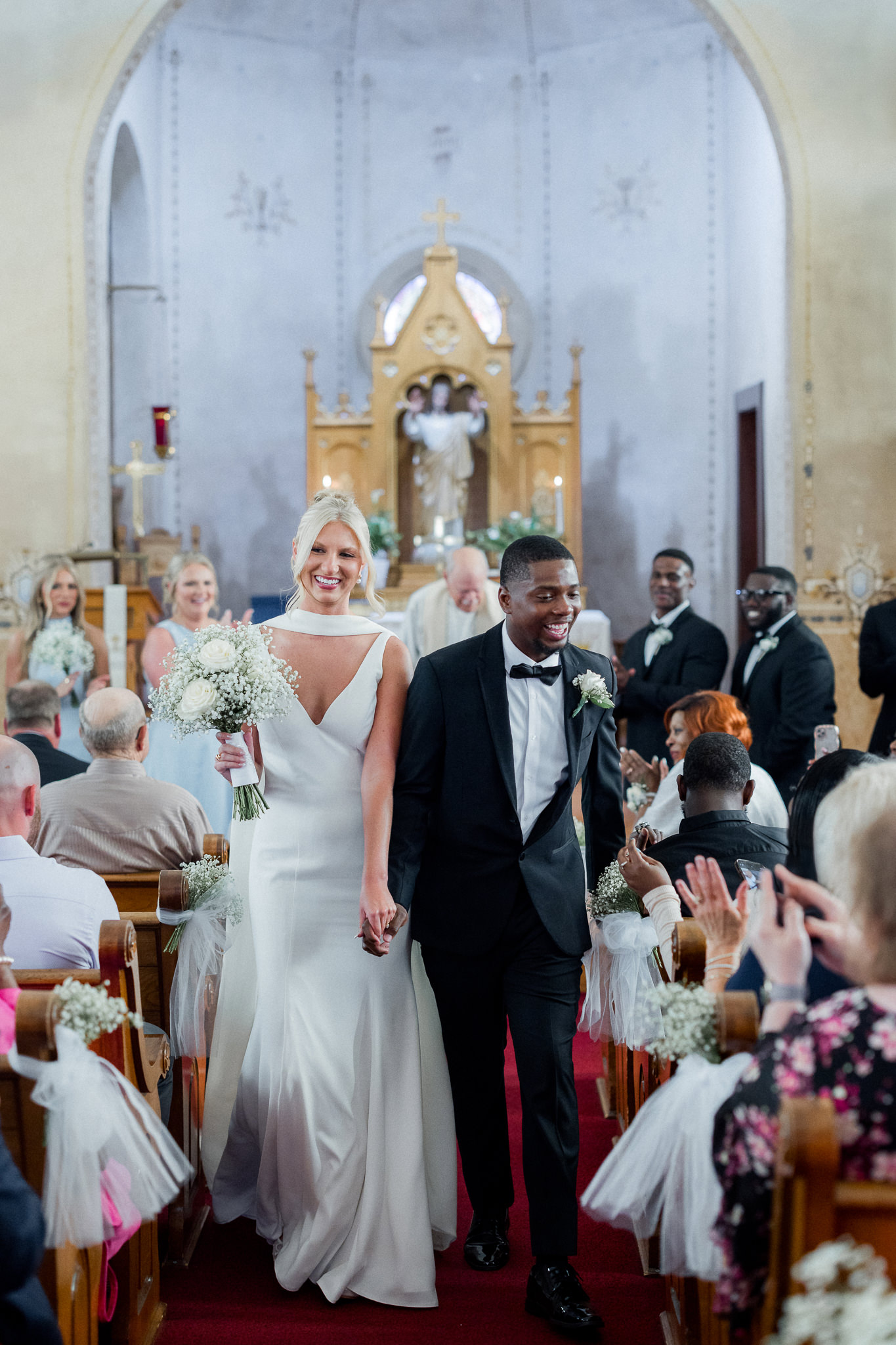 Just married! Bride and groom walk joyfully down the aisle as their loved ones cheer — photographed by Missouri wedding photographer Love Tree Studios.