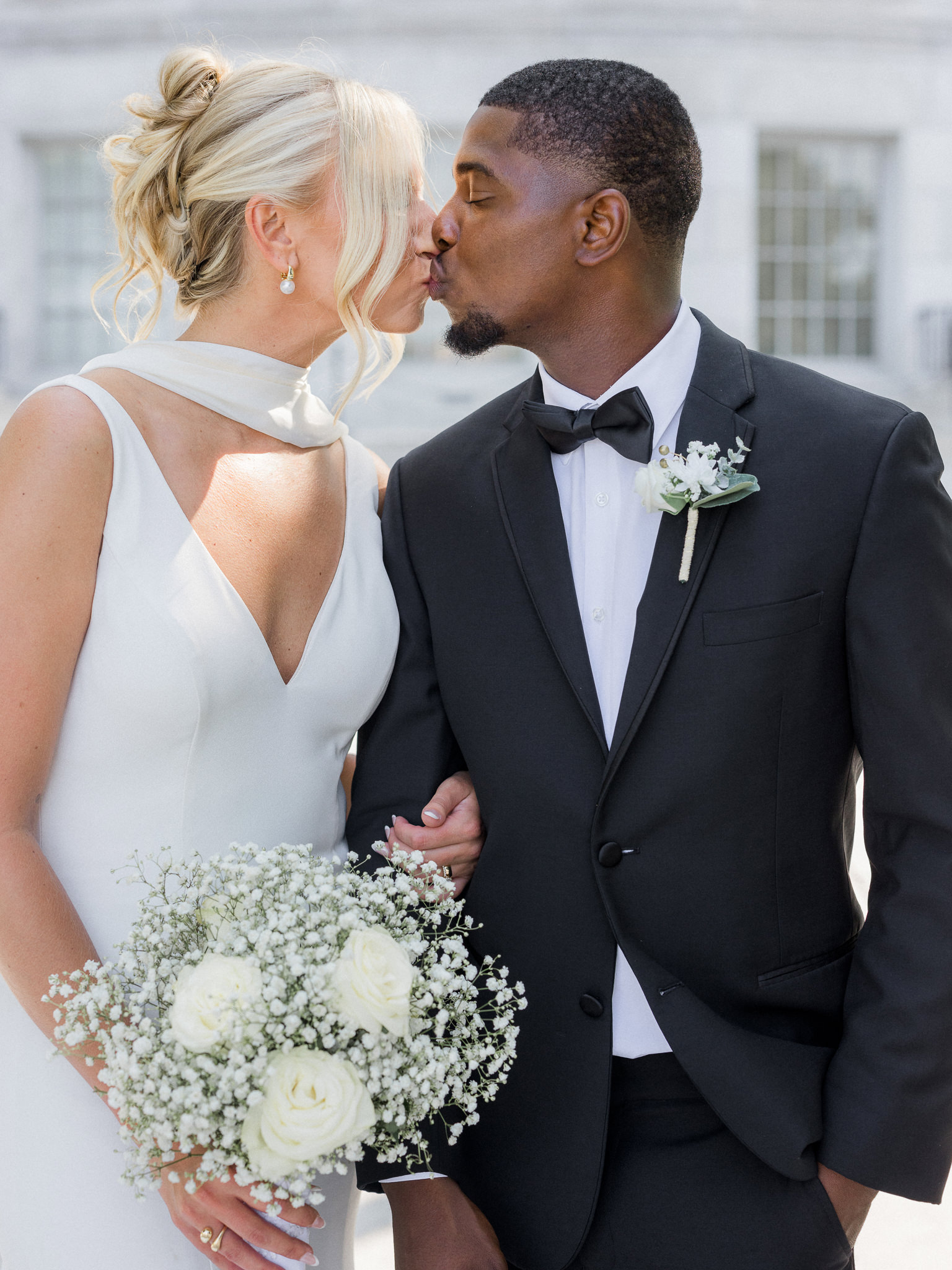 Close-up of bride and groom sharing a kiss, bride holding bouquet of roses and baby’s breath — photo by Missouri wedding photographer.