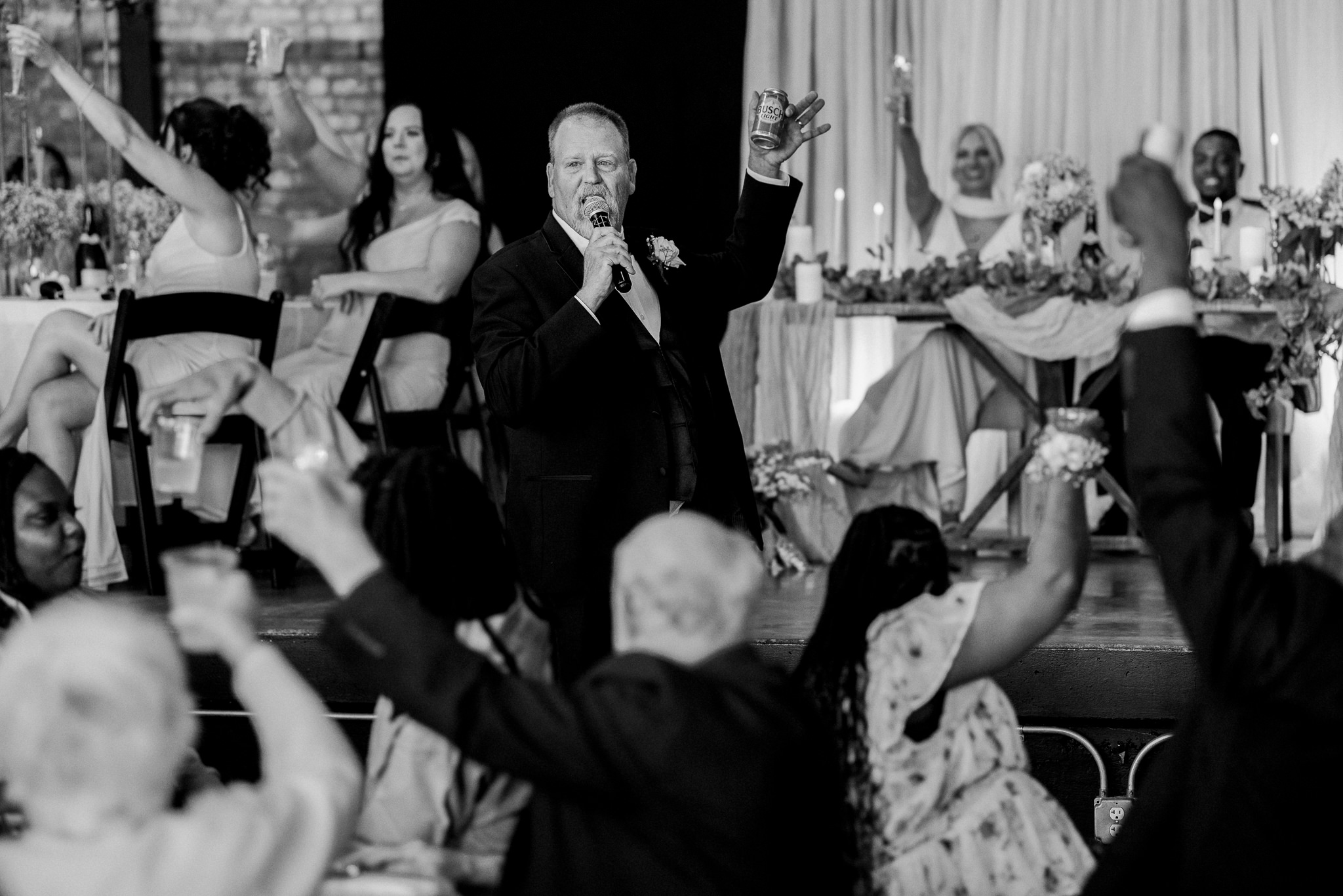 Father of the bride gives a heartfelt toast as wedding guests raise their drinks in celebration