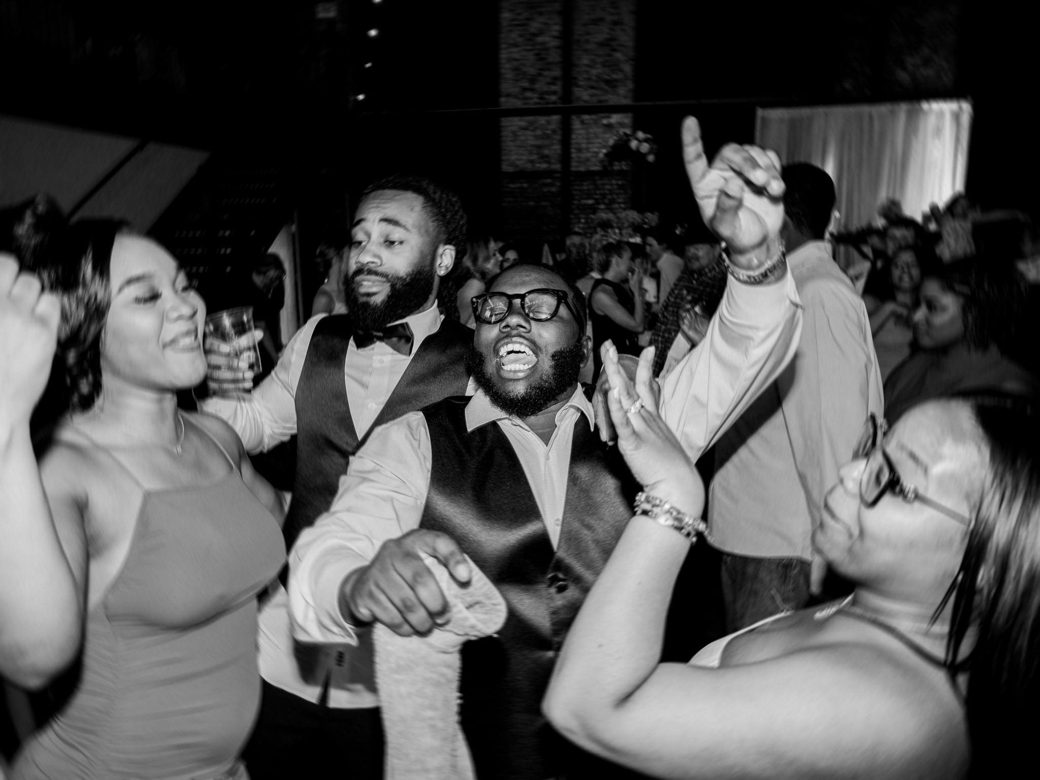 Group of wedding guests dance and celebrate late into the night on the reception floor.