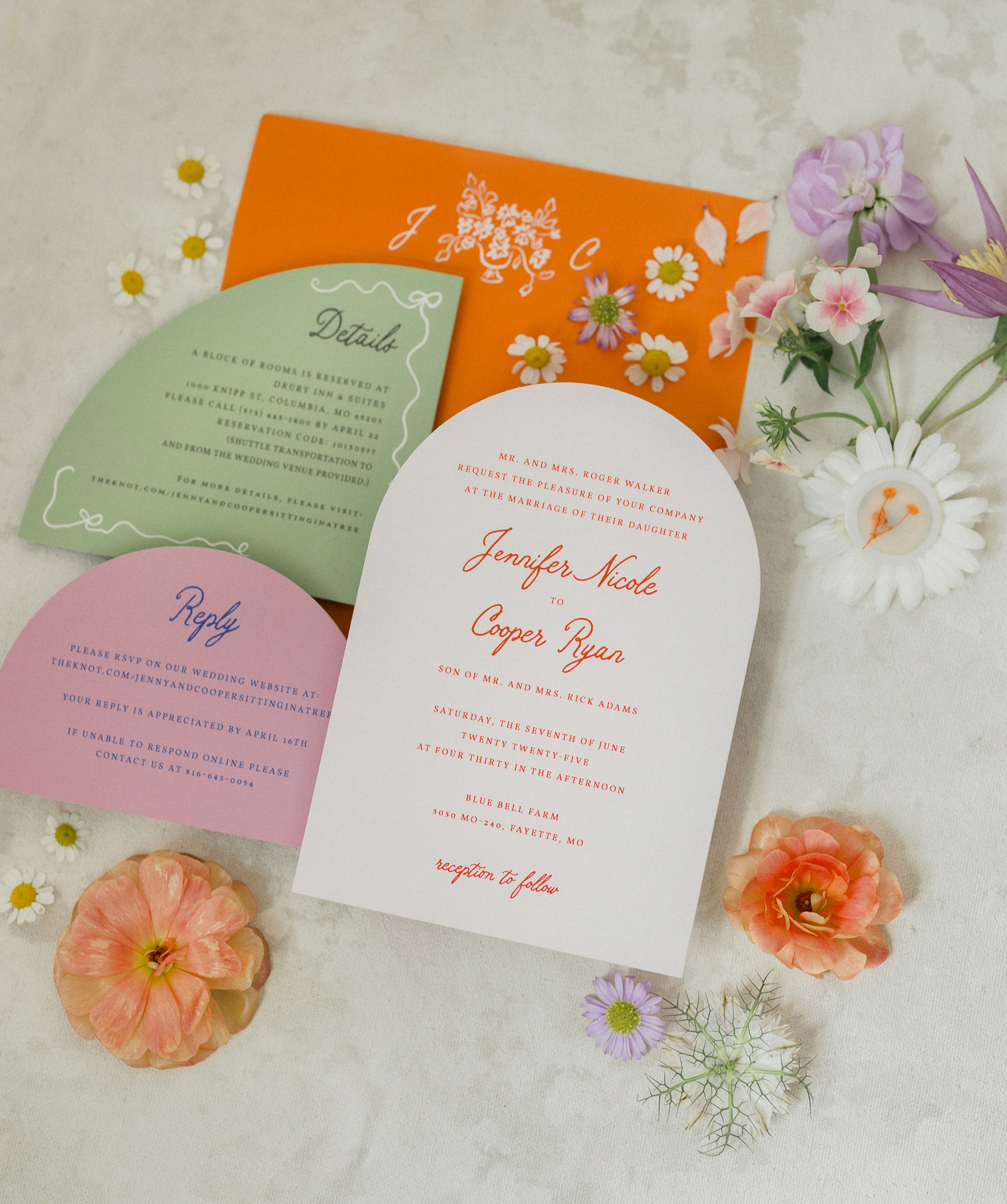 Colorful wedding invitation suite with modern arch-shaped cards in lavender, blush, and sage, styled with daisies and poppies.