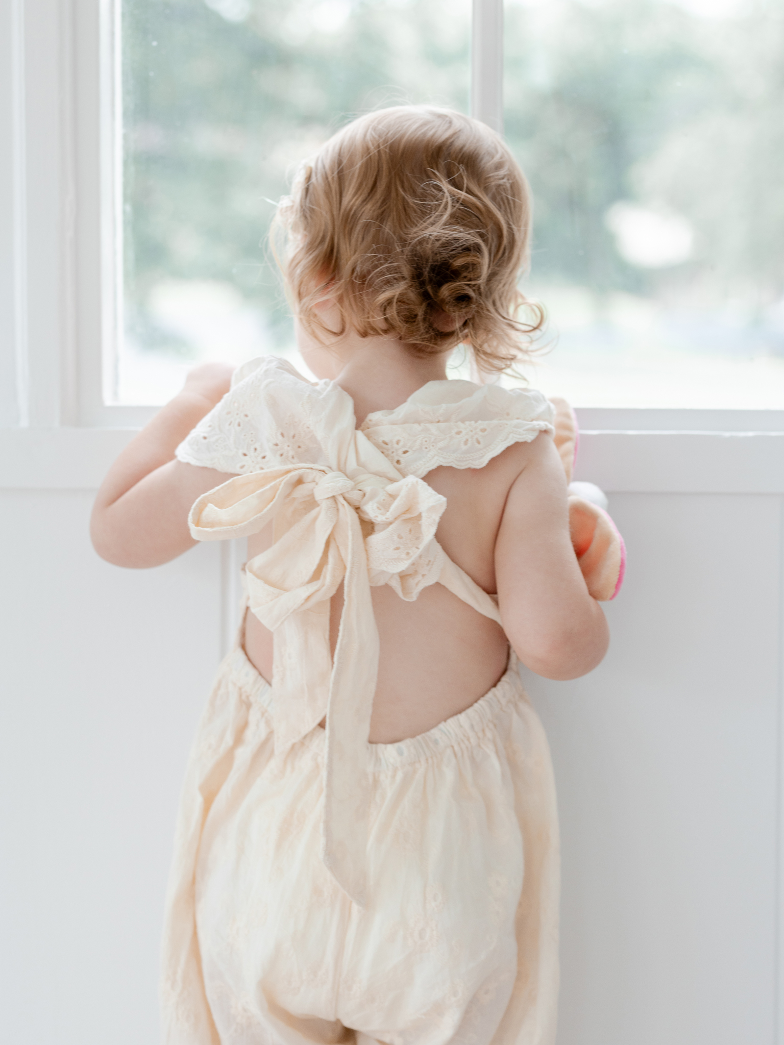 Back view of toddler Parker looking out the window during her Columbia, Missouri studio family photo session with Love Tree Studios.