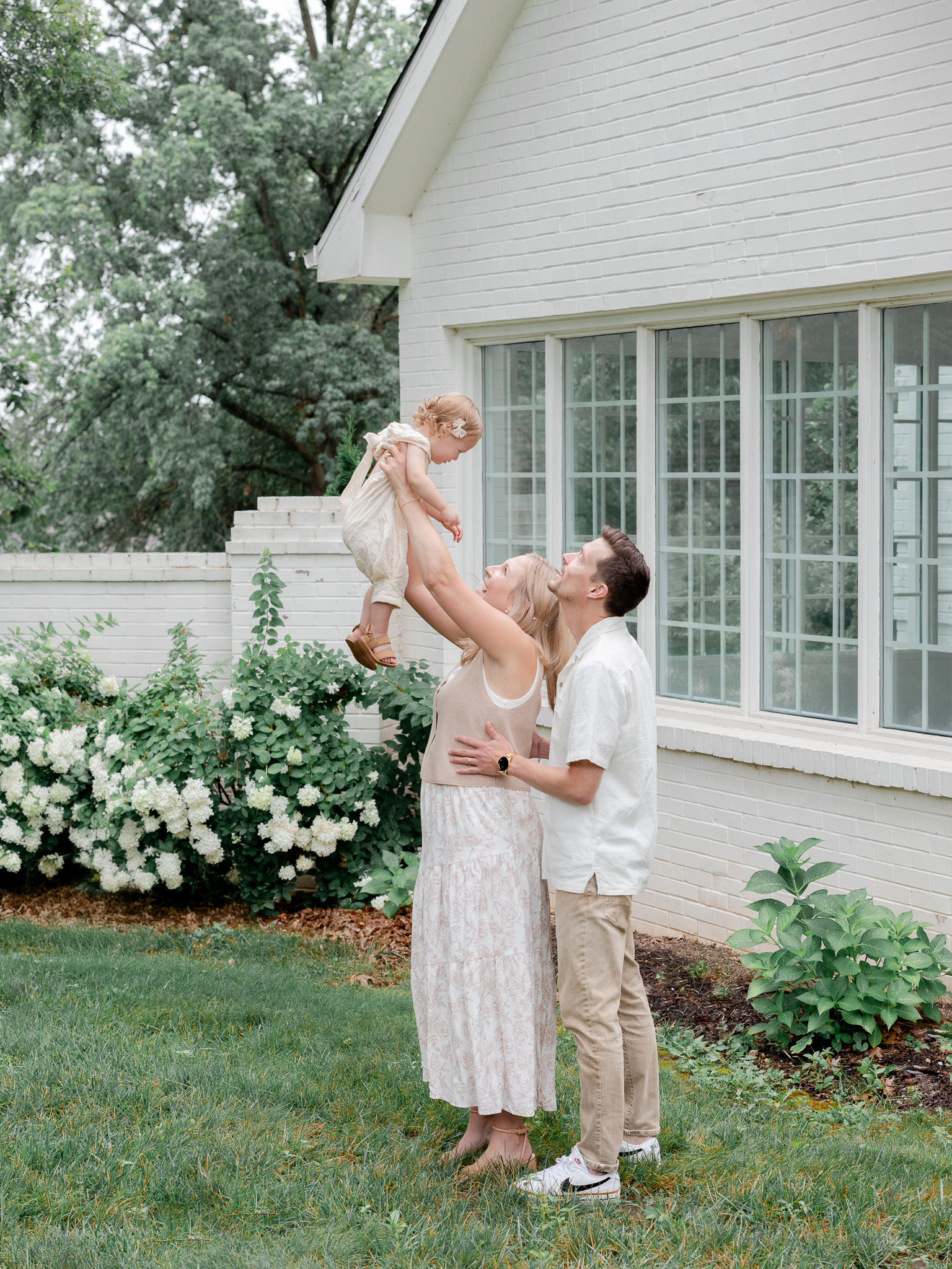 The Bradley family outside Love Tree Studios in Columbia, Missouri, lifting Parker during their studio family photos Missouri session.