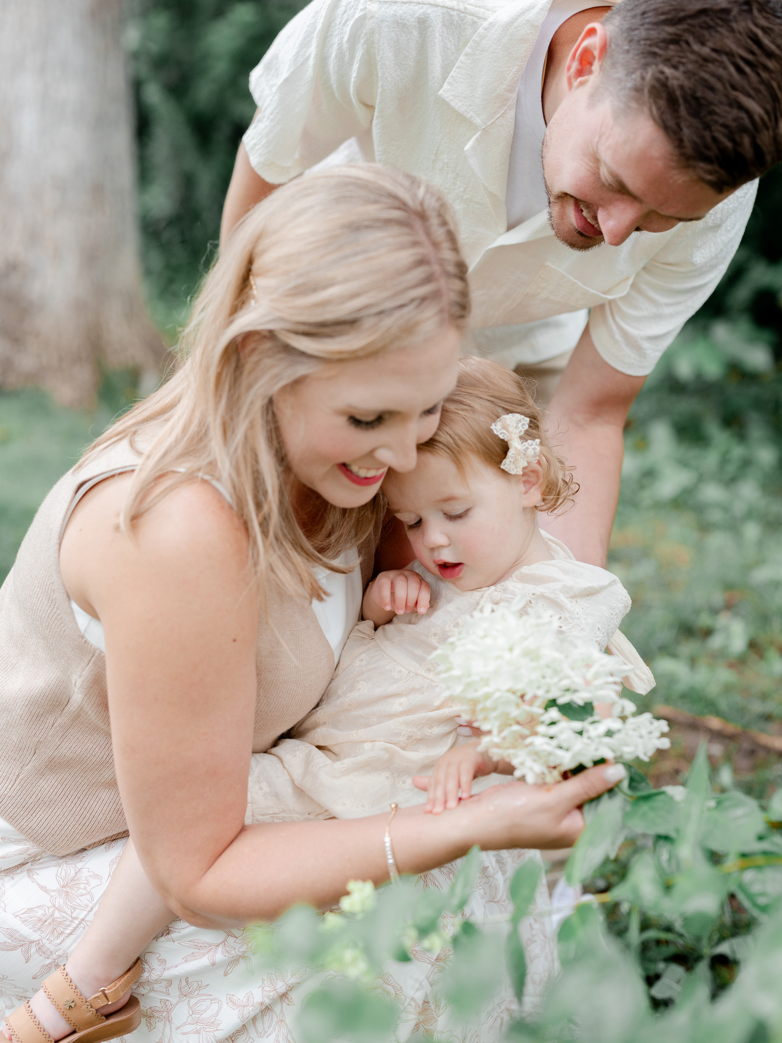 Candid moment of the Bradley family admiring hydrangeas with their daughter during their Columbia, Missouri studio family photo session at Love Tree Studios.