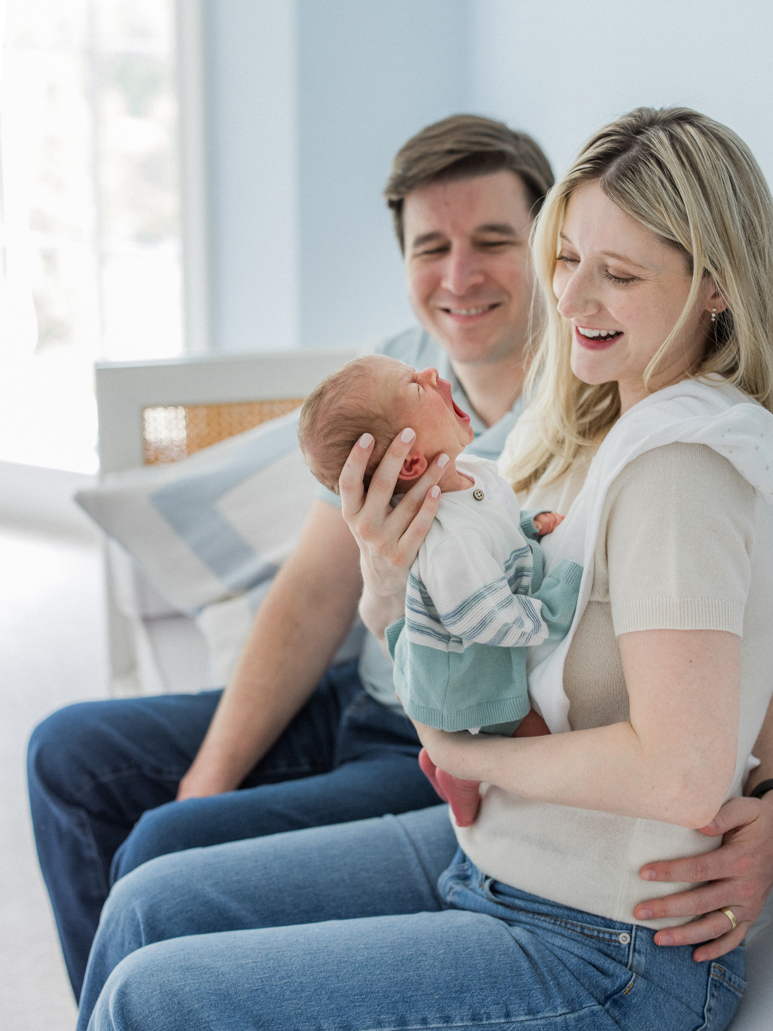 Sweet moment between parents holding their swaddled baby on a daybed during their Columbia Missouri newborn session.