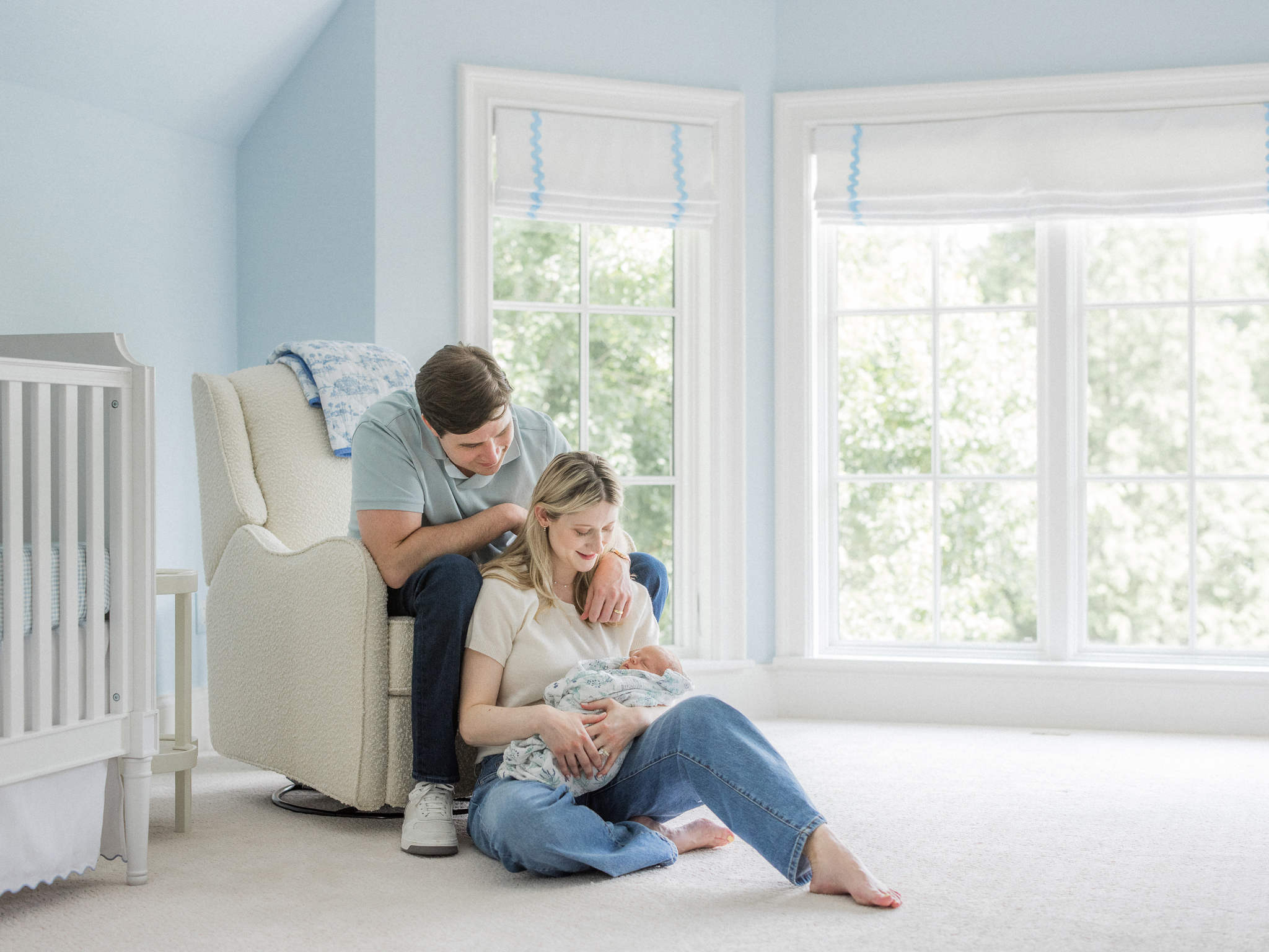 Parents sitting by the nursery window holding their baby during a Columbia Missouri newborn session.
