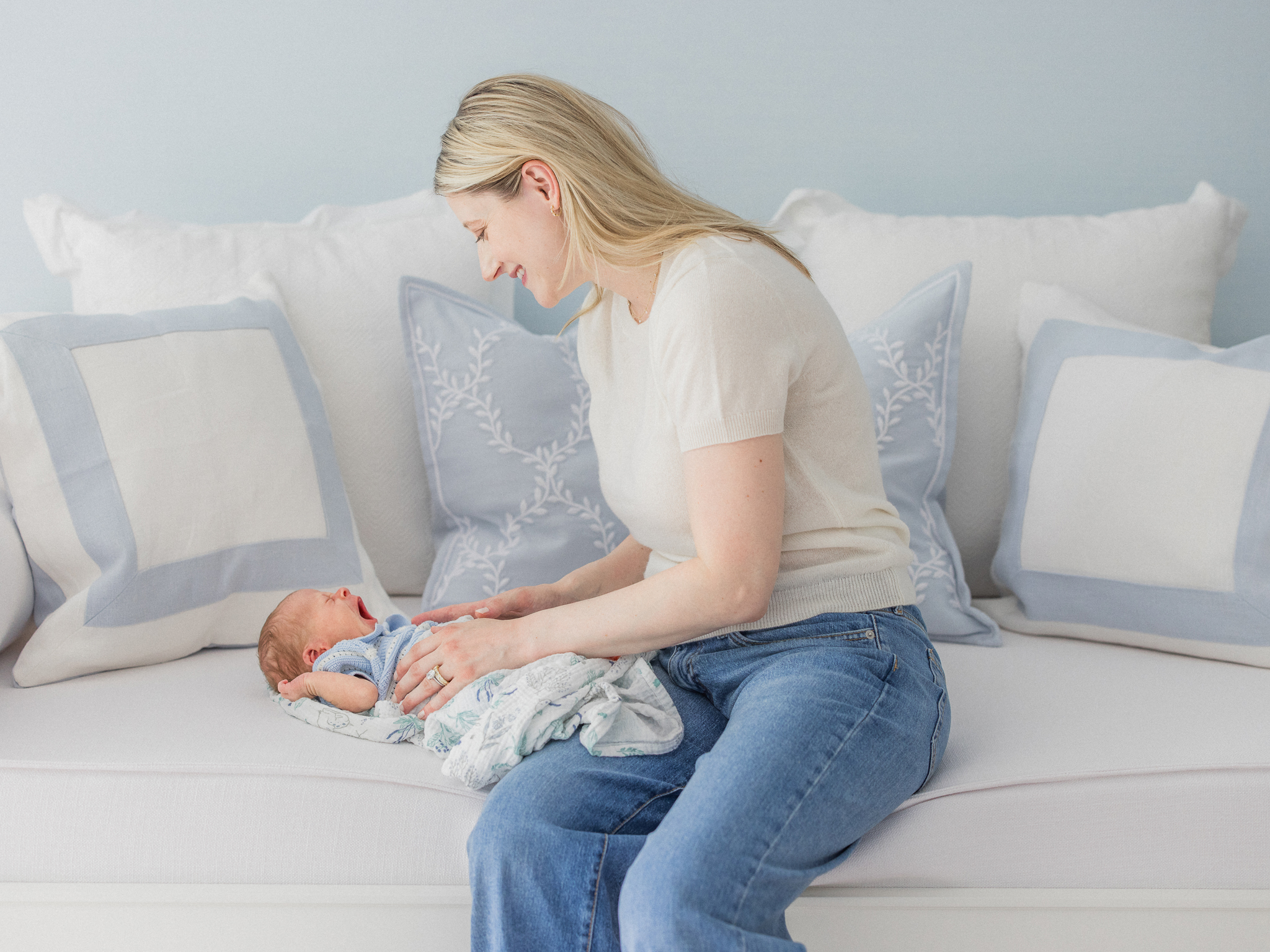 Mom smiling down at baby Win as he lays on a bench during their Columbia Missouri newborn session.
