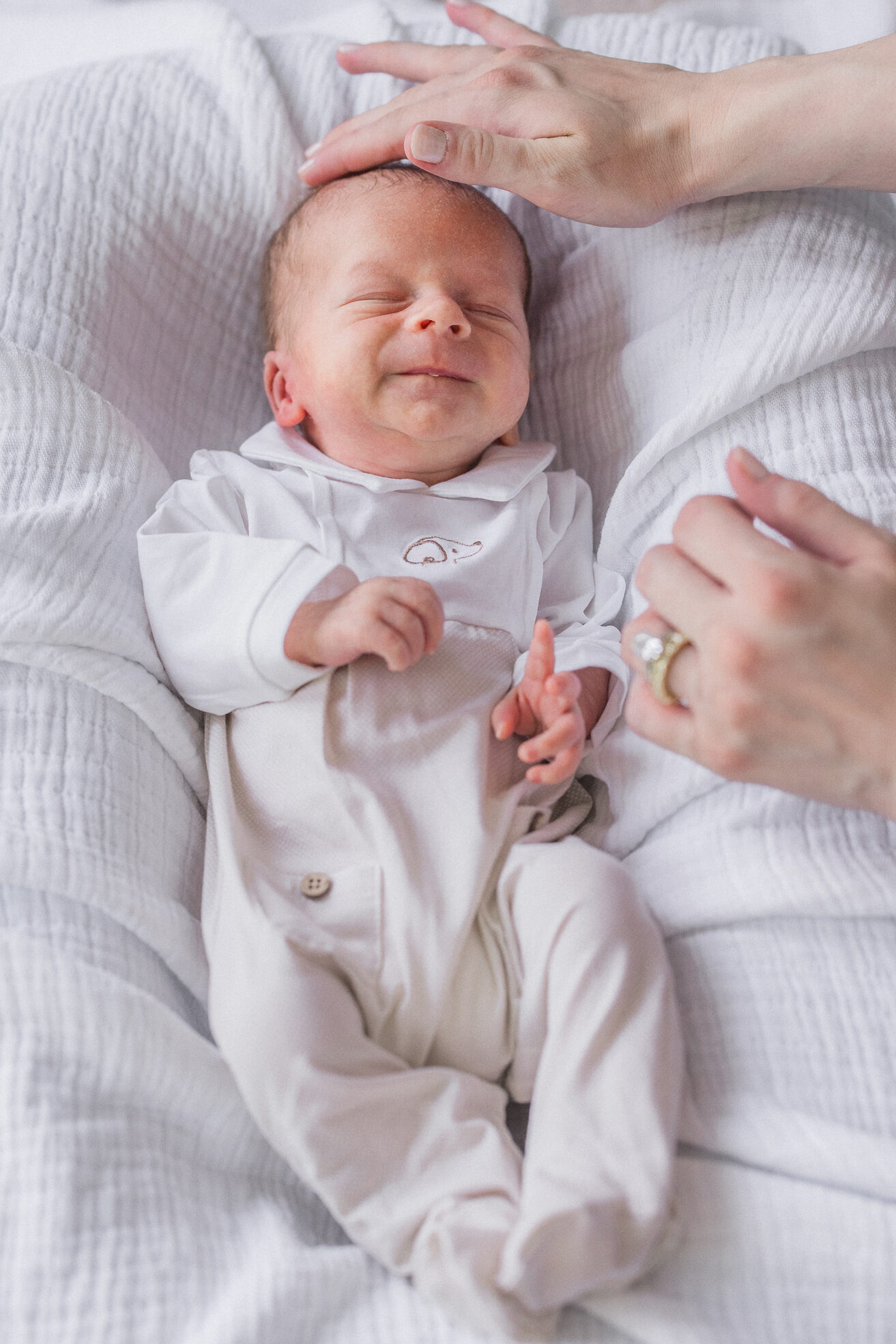 Close-up of baby Win swaddled and smiling as mom touching his forehead during a Columbia Missouri newborn session.