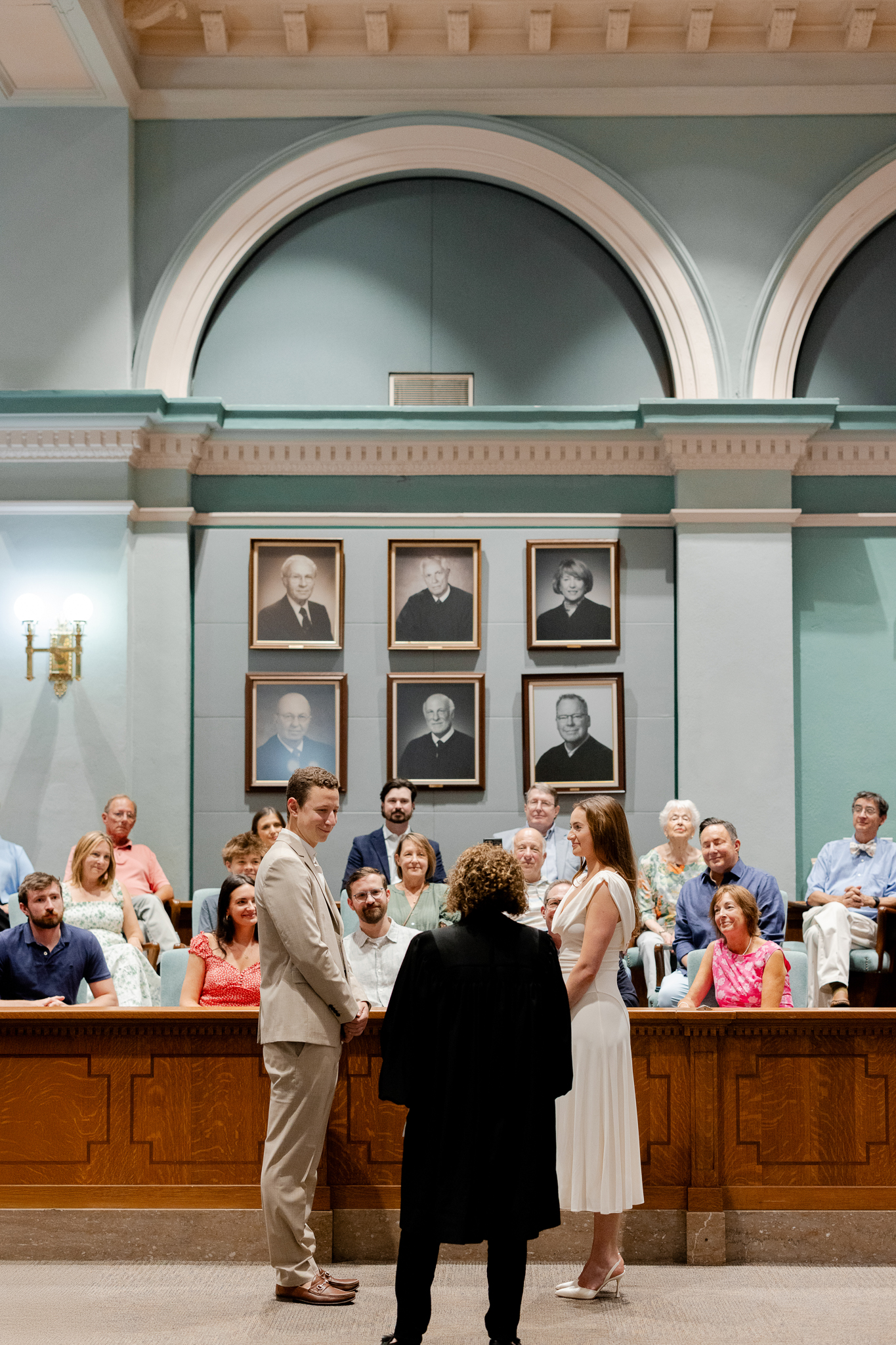 Arthur and Madison standing before the judge in a courtroom surrounded by family during their courthouse wedding in Columbia Missouri, captured by Love Tree Studios.