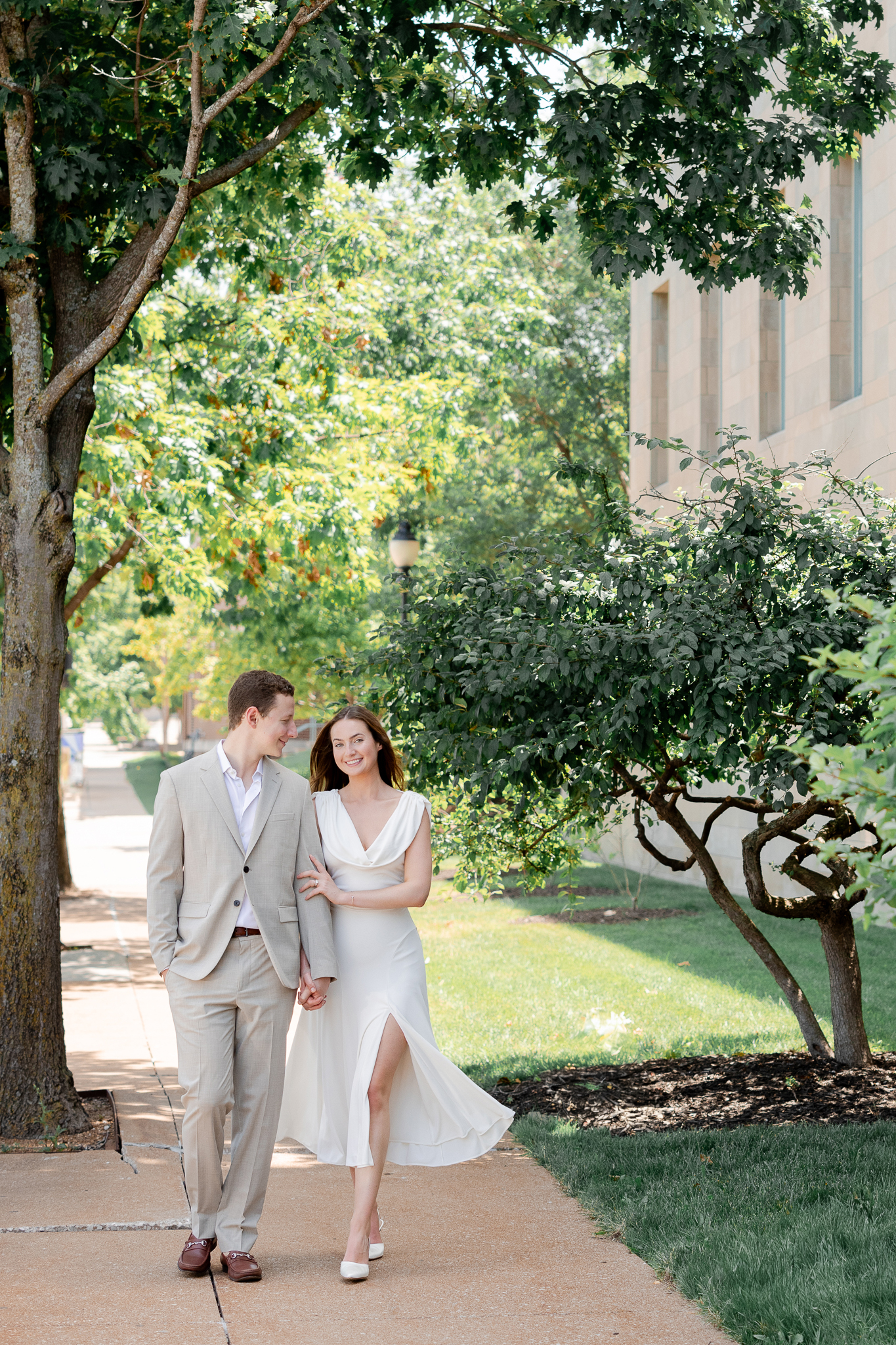 Arthur and Madison walking hand in hand under the trees beside the Boone County Courthouse – courthouse wedding in Columbia Missouri photographed by Love Tree Studios.