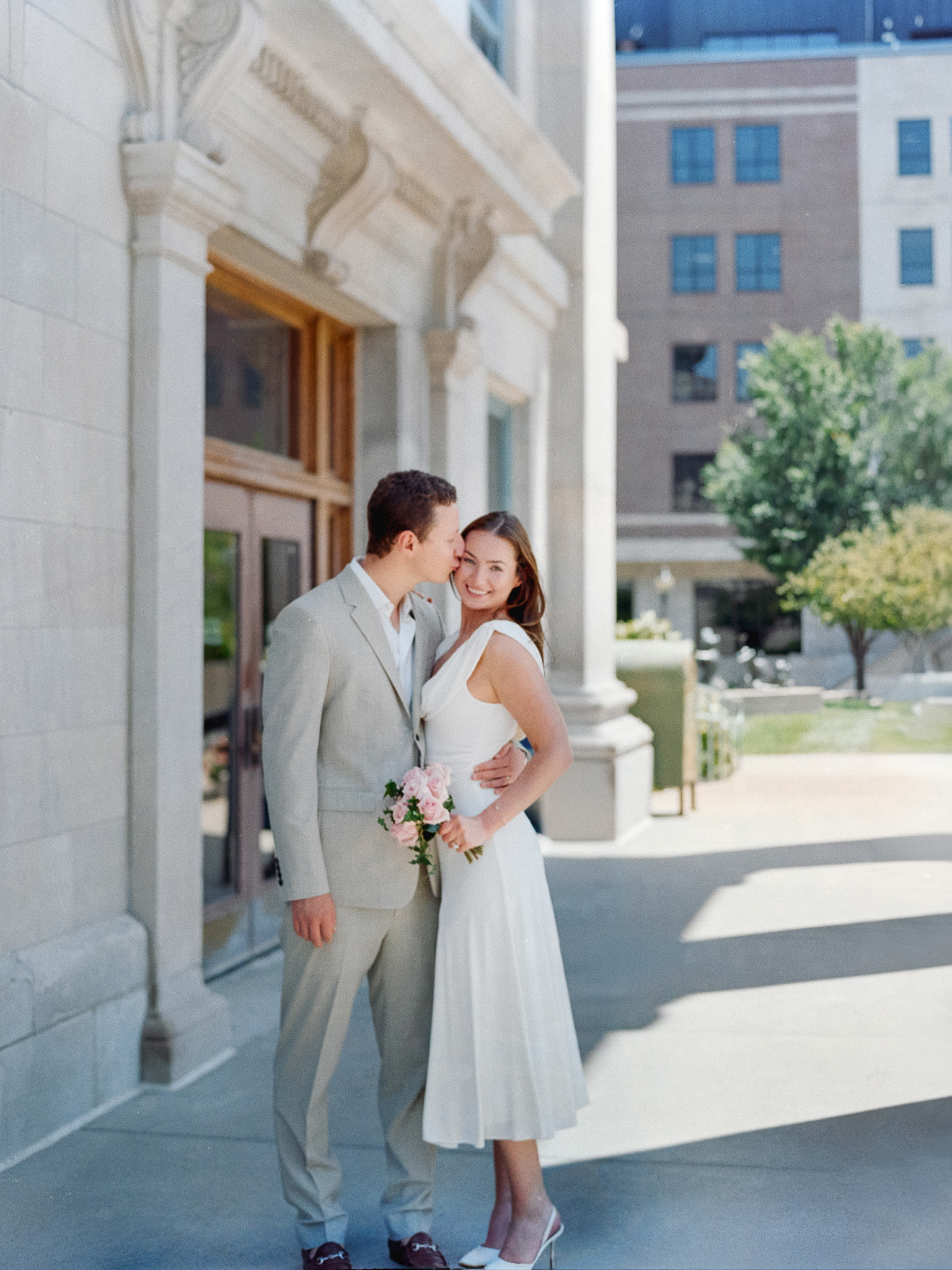 Film image of Arthur kissing Madison’s temple outside the Boone County Courthouse – courthouse wedding in Columbia Missouri on film by Love Tree Studios.