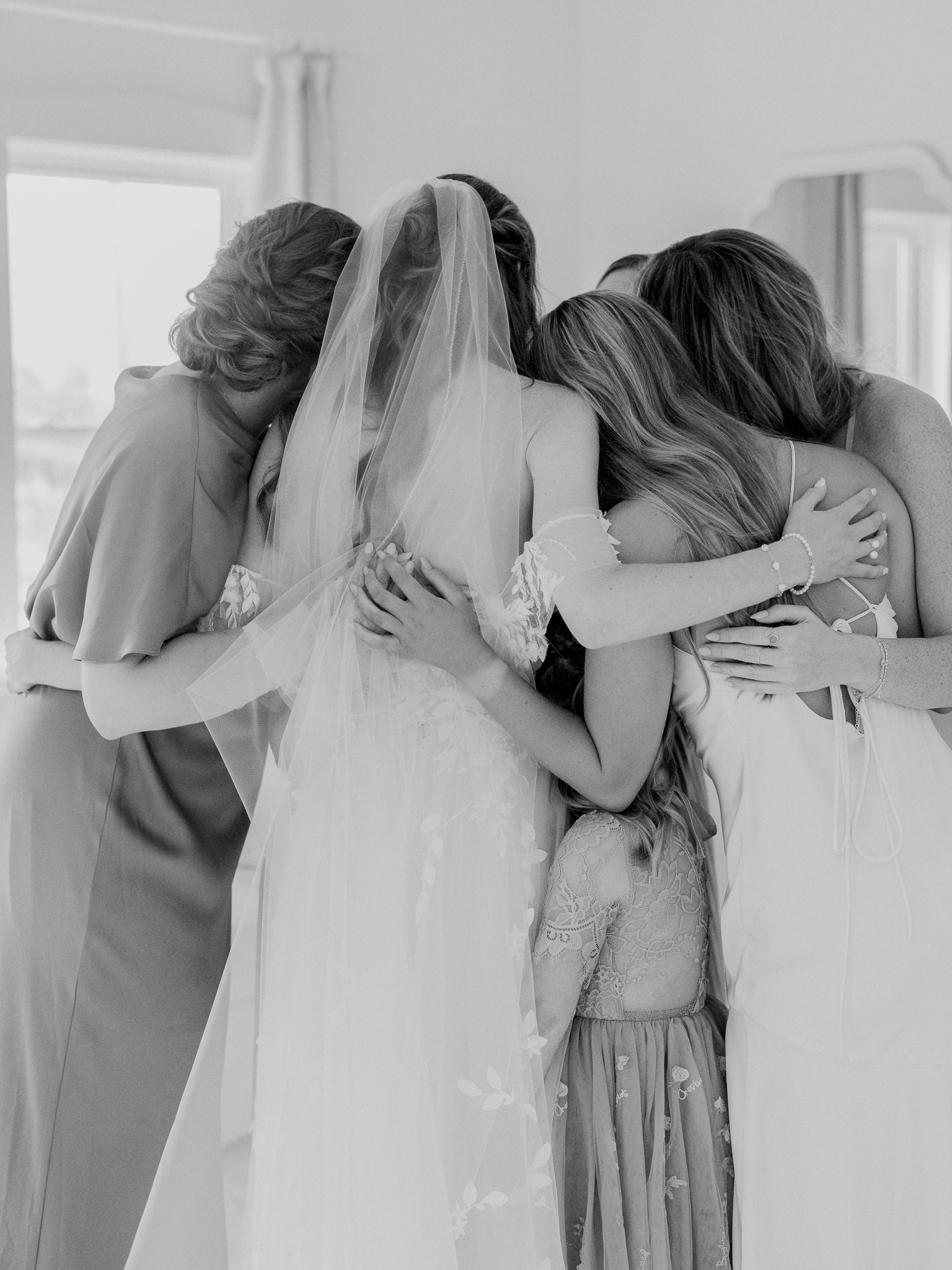Bride and bridesmaids share a heartfelt group hug before the ceremony.
