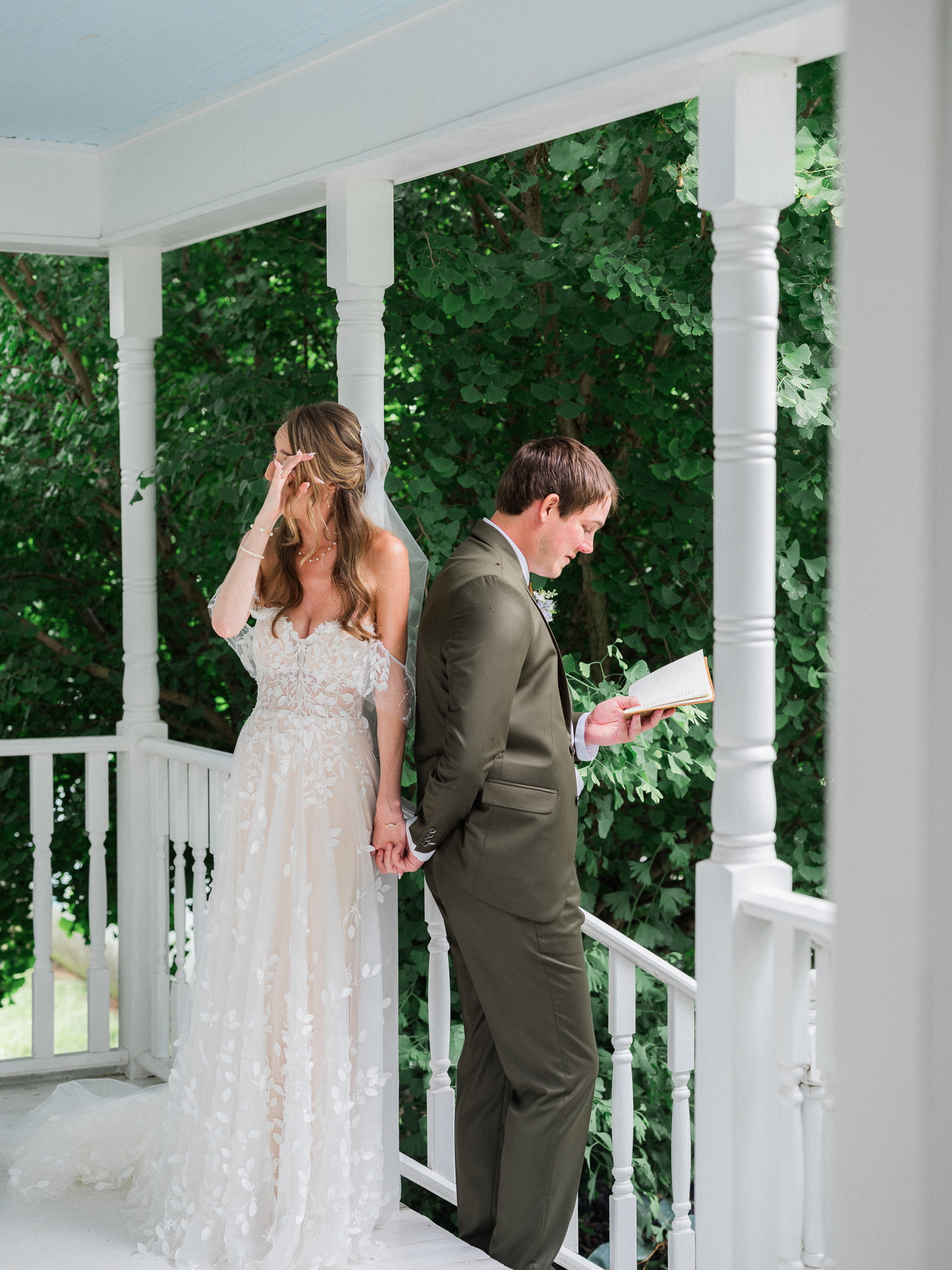 Emotional moment as bride and groom stand back-to-back holding hands without seeing each other at a Blue Bell Farm wedding.