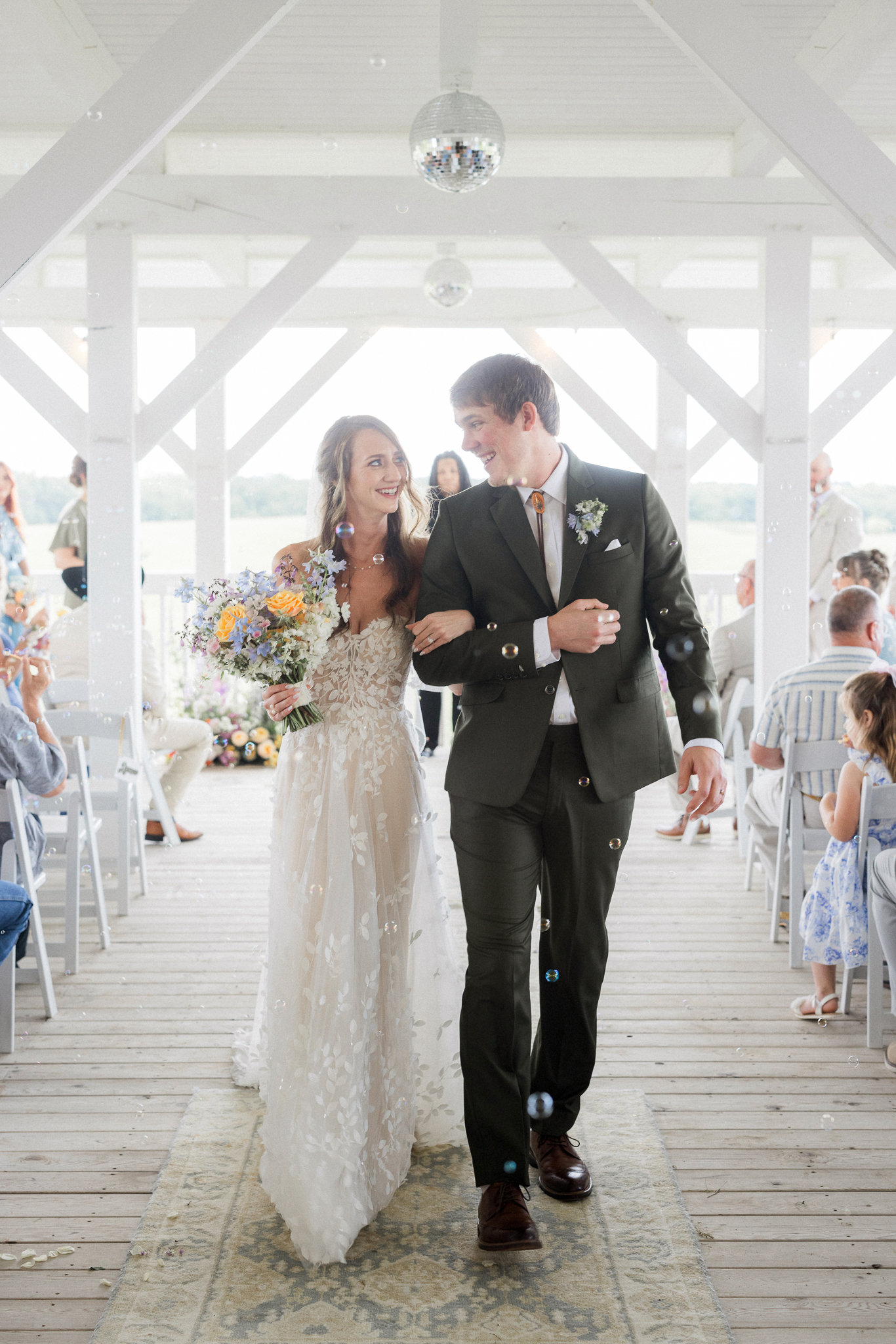 Walking back down the aisle as newlyweds at their Blue Bell Farm wedding, surrounded by love and bubbles.