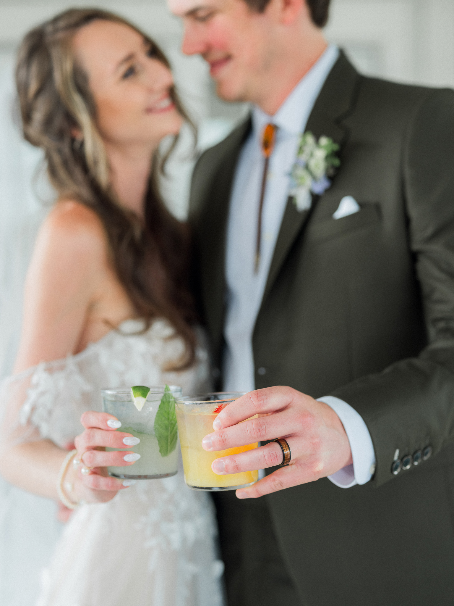 Bride and groom smiling with their signature cocktails in hand during a joyful candid moment.