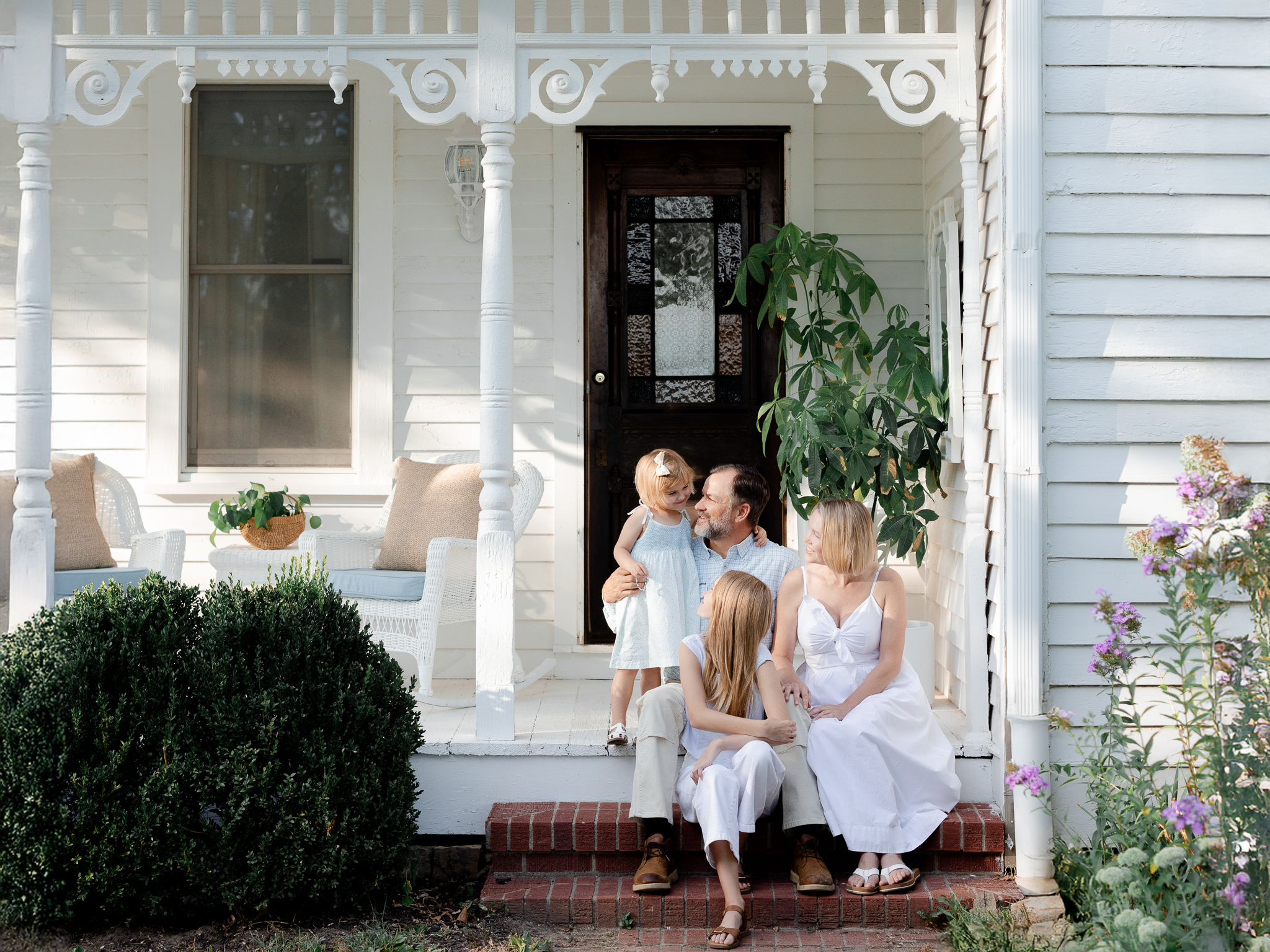 Family on the porch steps of their farmhouse, photographed by Missouri family photographer Love Tree Studios.