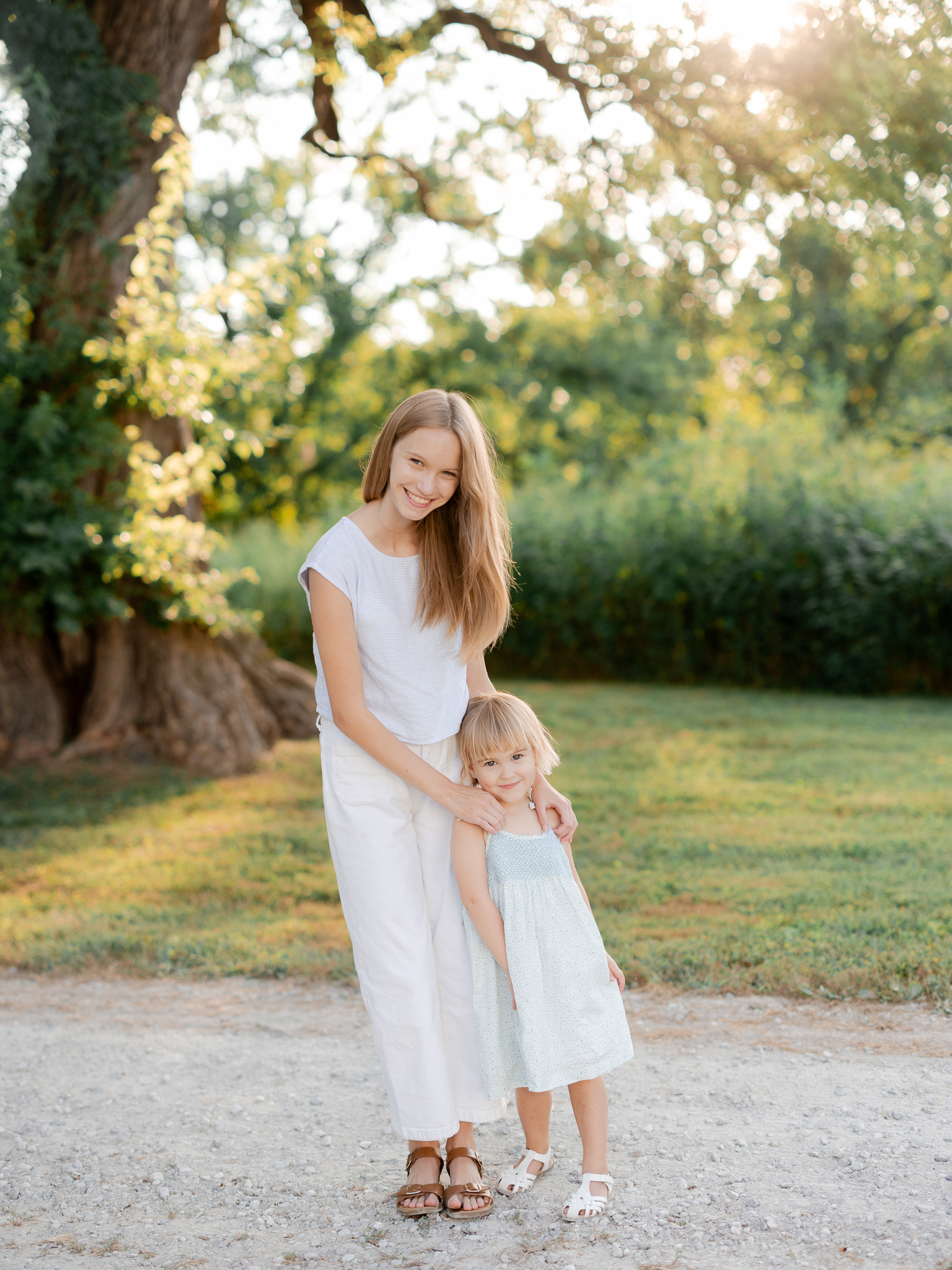 Sisters smiling together outdoors in golden light, Missouri family portraits.