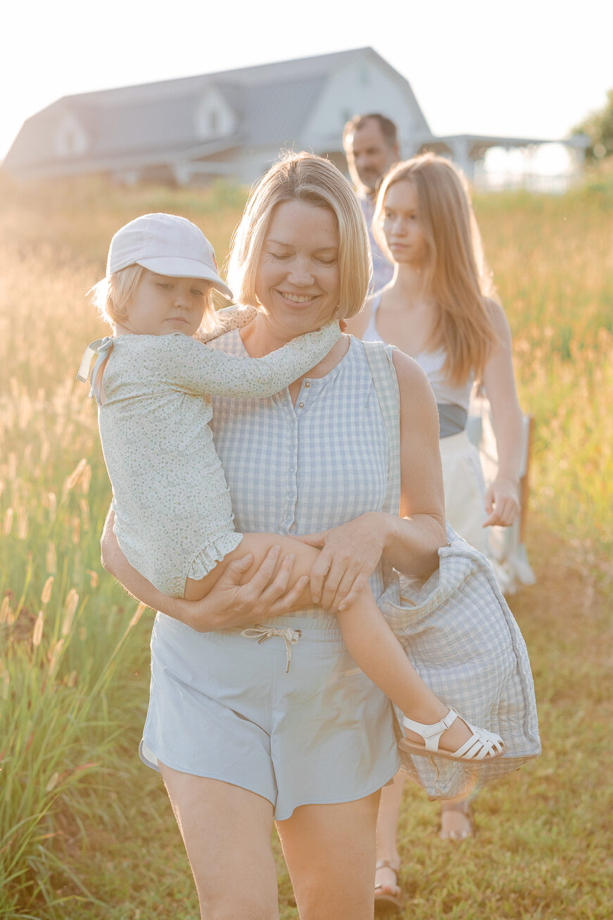Mother carrying daughter through tall grass at sunset — Love Tree Studios family portraits.