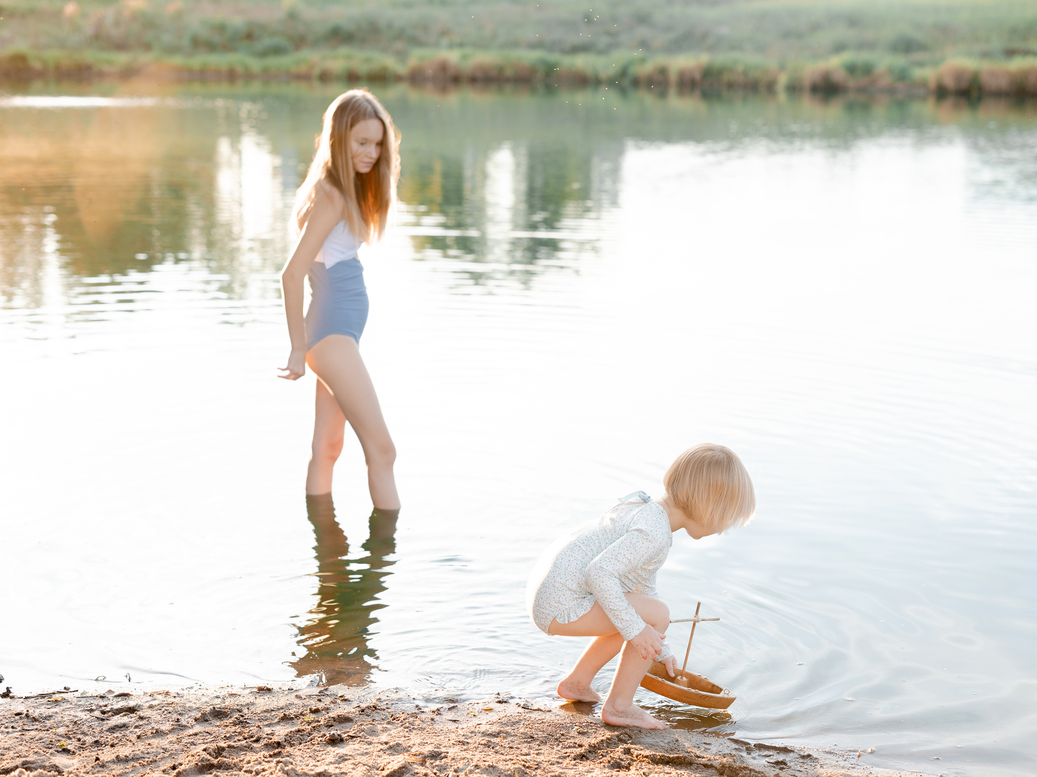 Sisters wading and playing with a toy sailboat in the lake — Missouri family photography.