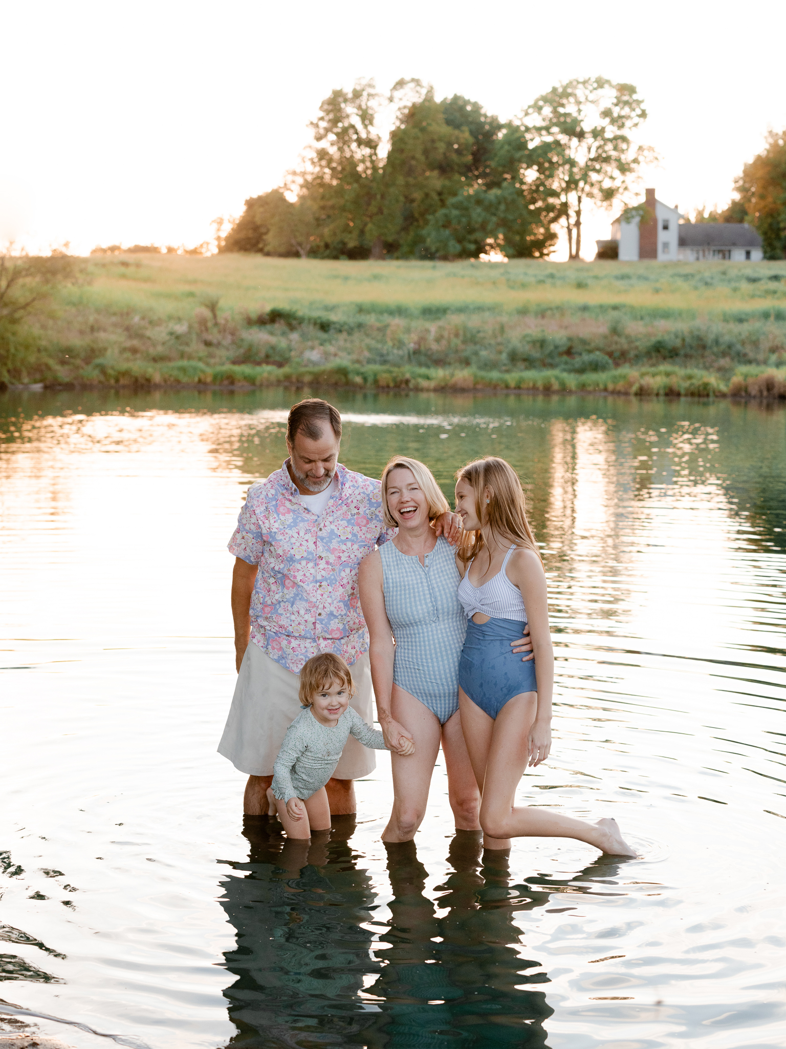 Family standing together in the lake at sunset — Missouri family photographer Love Tree Studios.