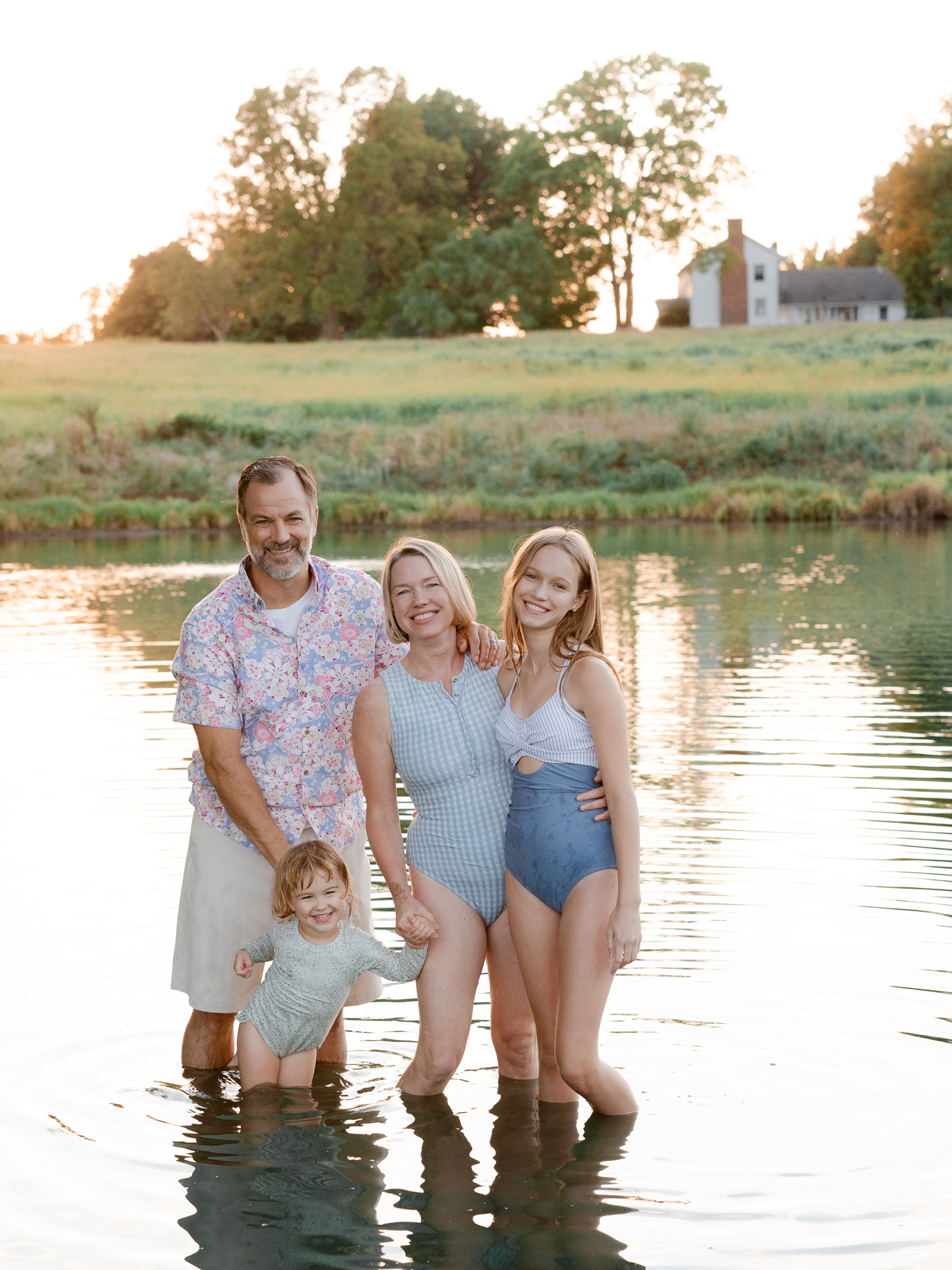 Family portrait standing in the lake with golden light reflections — Love Tree Studios.