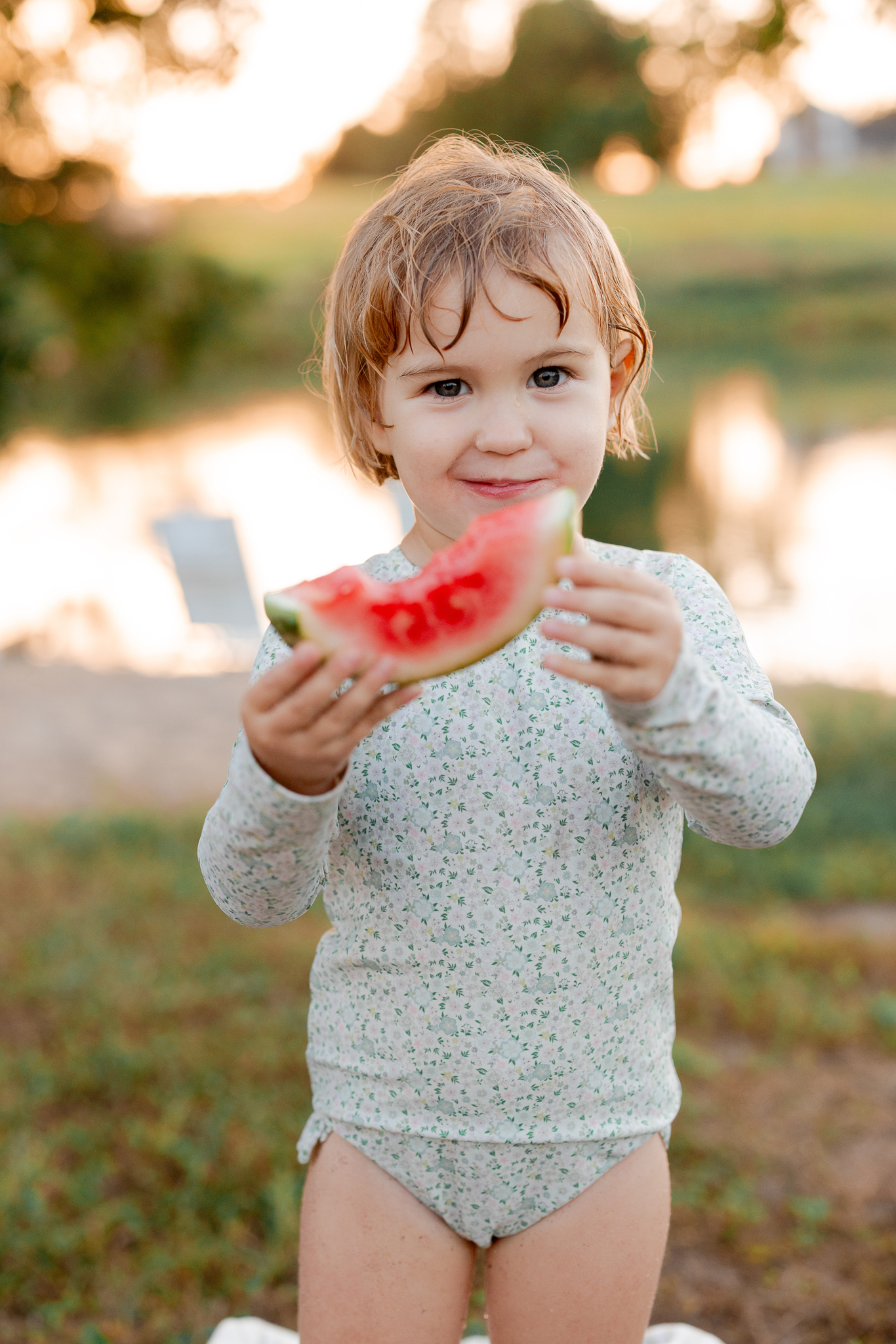 Young daughter smiling while holding a slice of watermelon — Missouri family photographer Love Tree Studios.