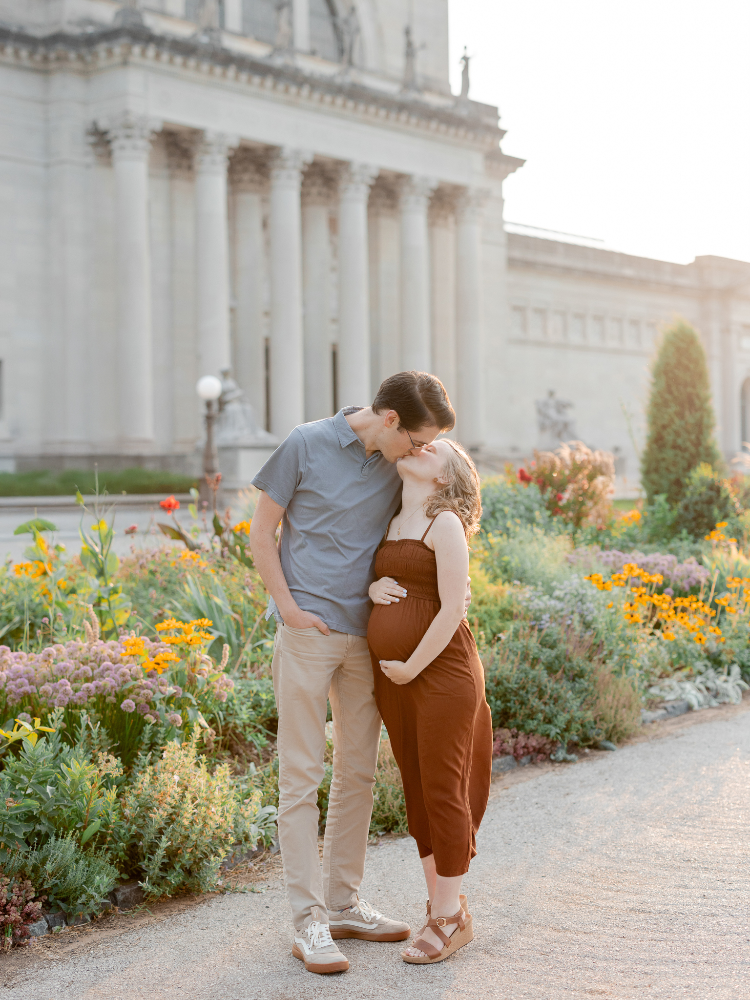 Husband kisses his wife’s forehead as they share a maternity moment in front of the St. Louis Art Museum, photographed by Love Tree Studios.