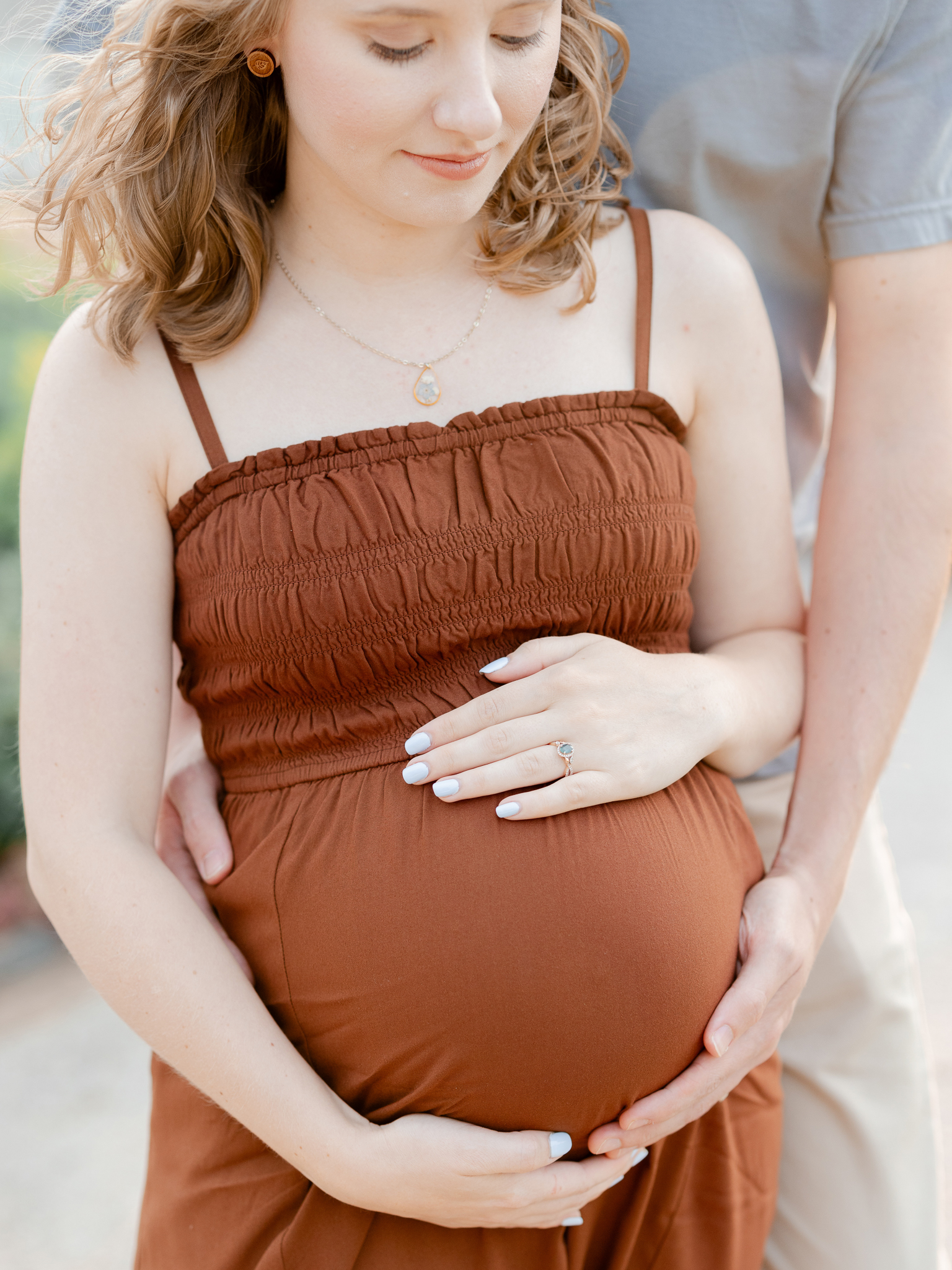 Close-up of hands resting on a baby bump during a maternity session at Art Hill in St. Louis by Love Tree Studios.