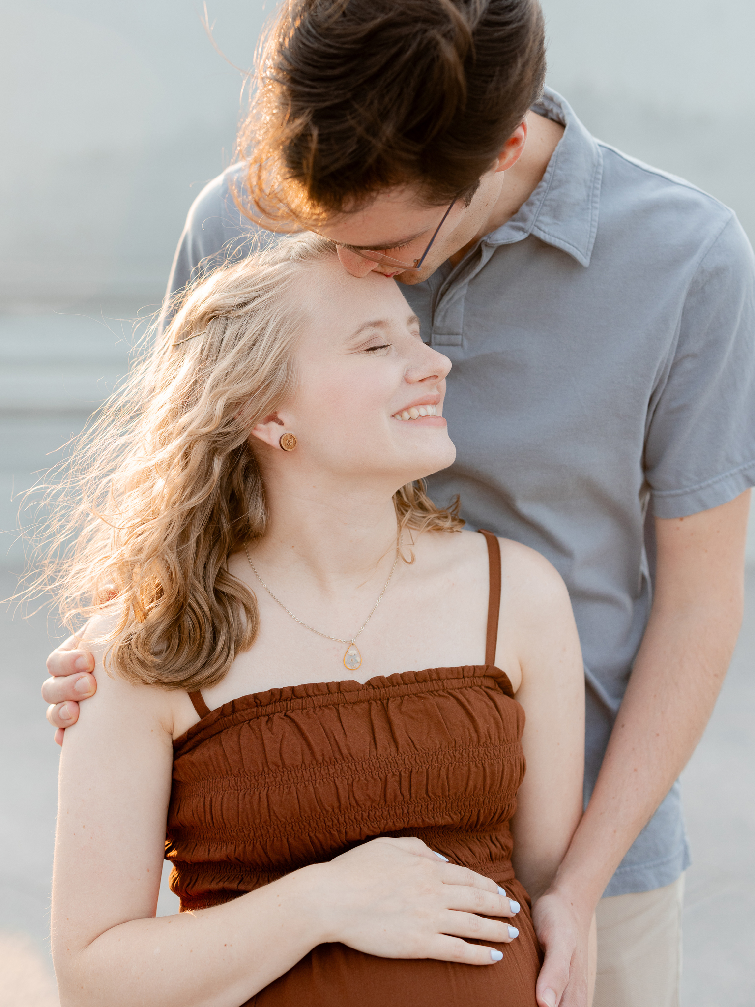 Parents-to-be share a kiss in front of the St. Louis Art Museum during their golden hour maternity photos with Love Tree Studios.