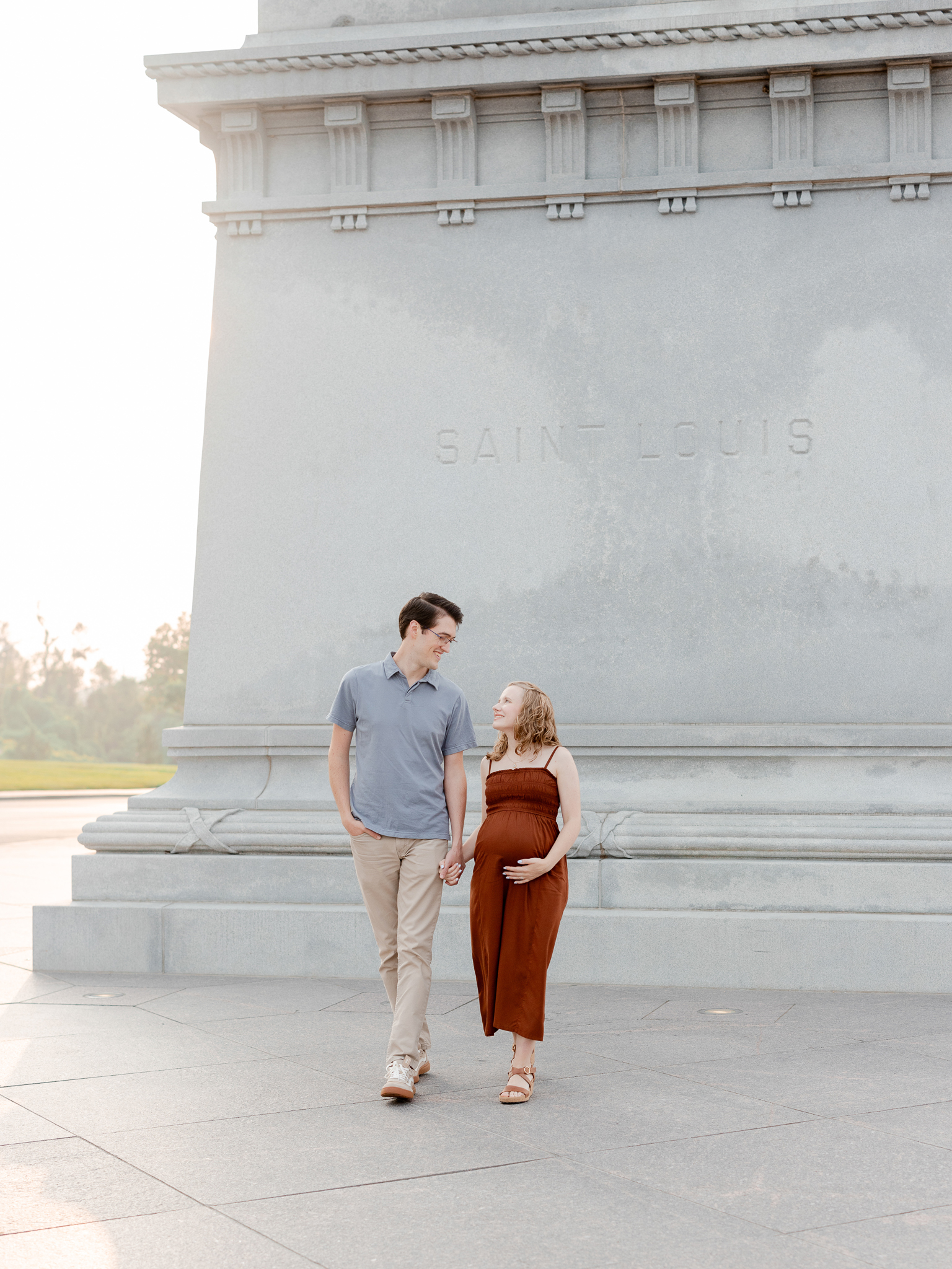 Couple walking hand-in-hand through Forest Park’s Art Hill during their maternity session with Love Tree Studios.