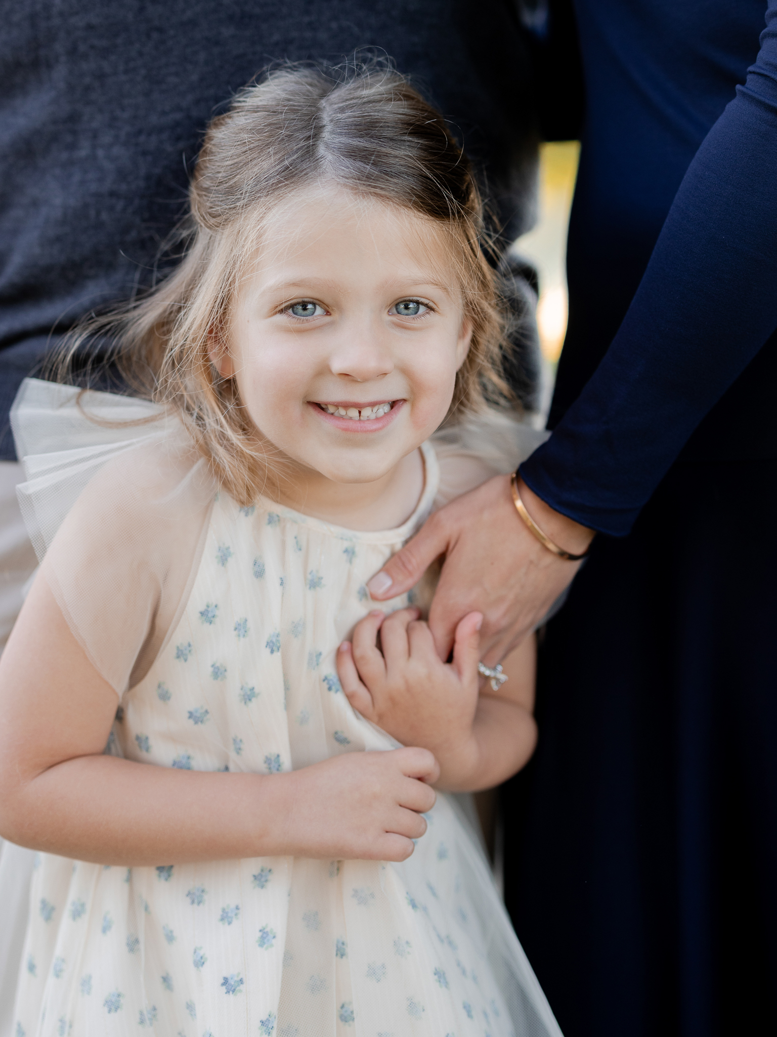 Close-up of little girl smiling while holding her mother’s hand – Columbia Missouri sunrise family photography.