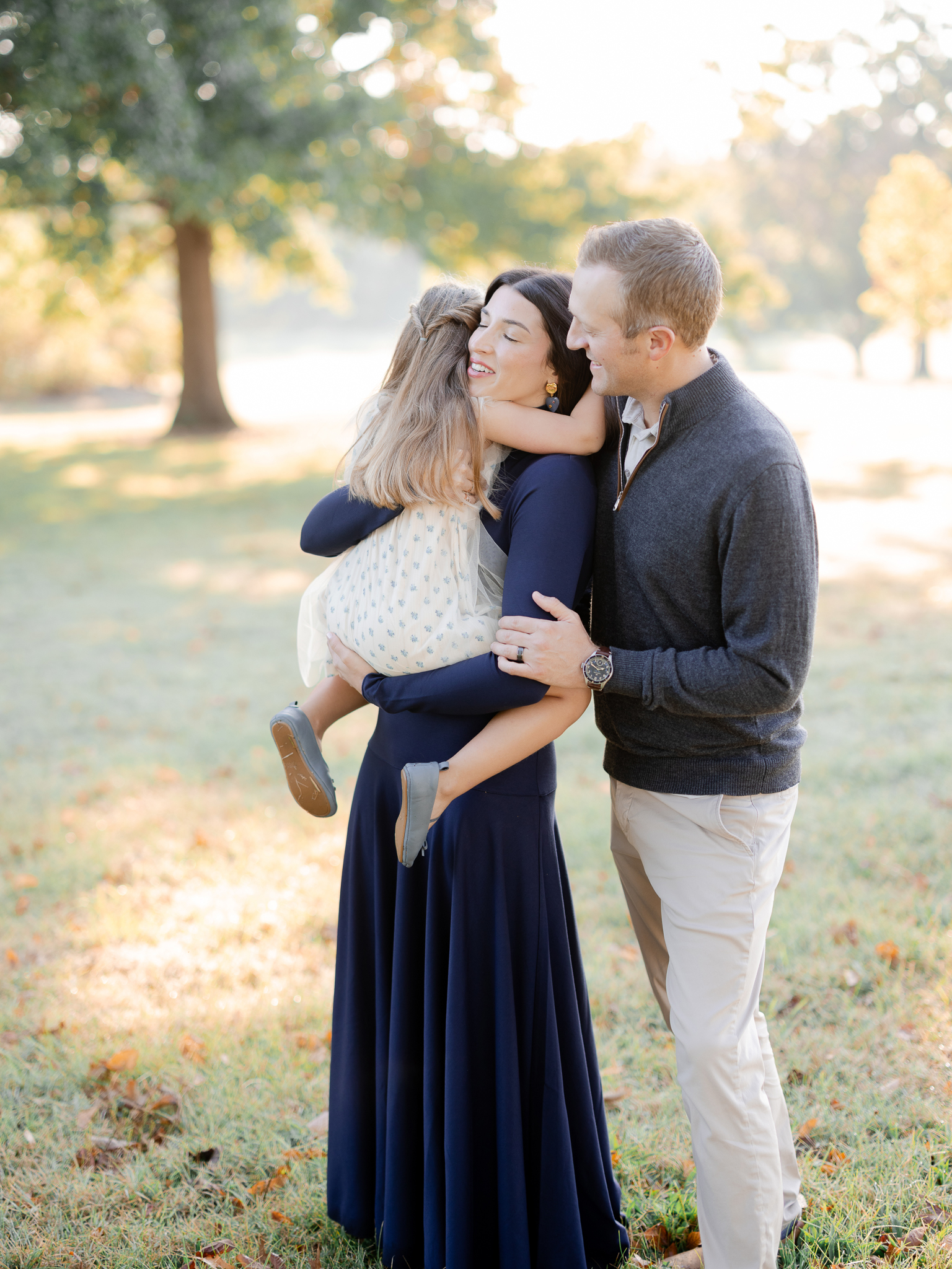 Family cuddling together outdoors in warm golden light – Love Tree Studios sunrise family session Columbia Missouri.