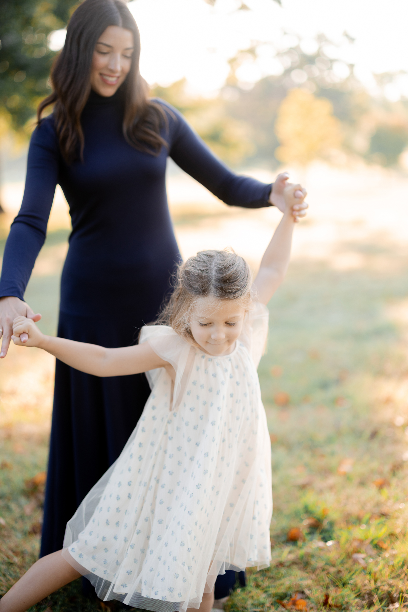 Mother twirling with her daughter in a playful moment – sunrise family photos Columbia Missouri lifestyle session.
