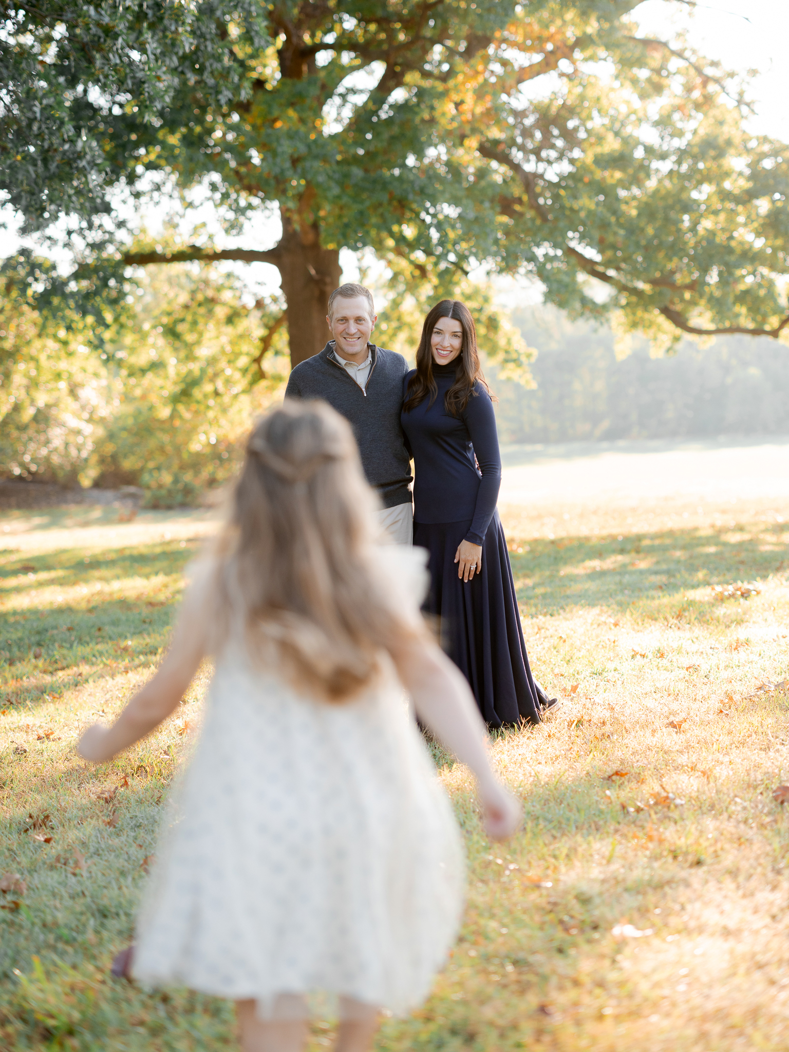 Family sitting together under a large oak tree, cuddling in the morning glow – sunrise family session Columbia Missouri.