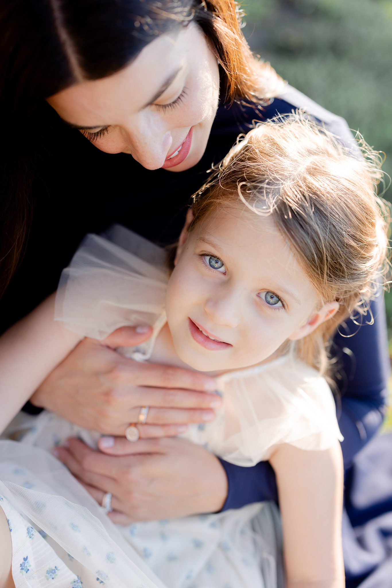 Parents and daughter snuggled close, smiling at the camera – sunrise family portraits Columbia Missouri by Love Tree Studios.