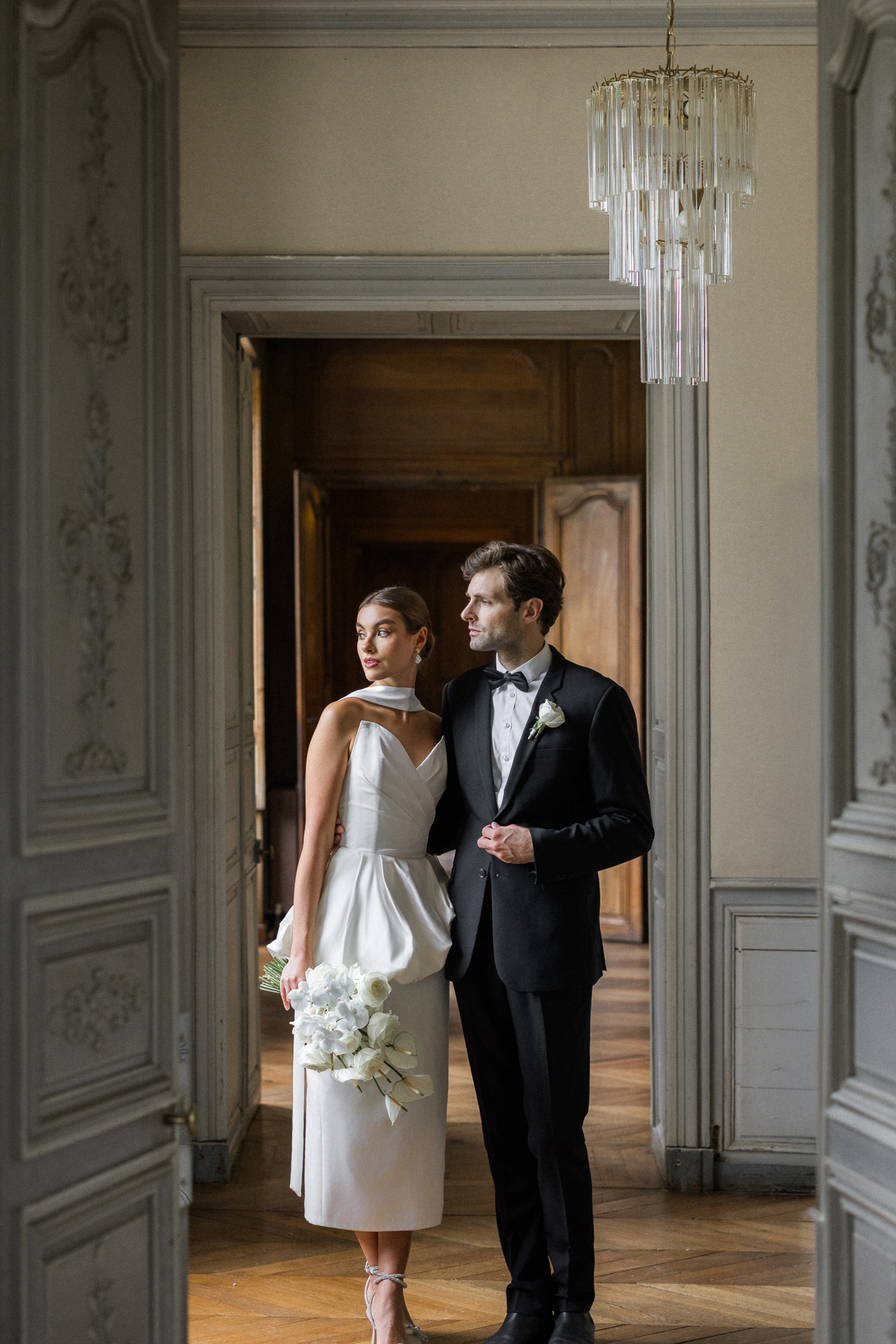 Couple standing in the doorway of Château de Thauvenay, surrounded by classic French architecture, photographed by Love Tree Studios.