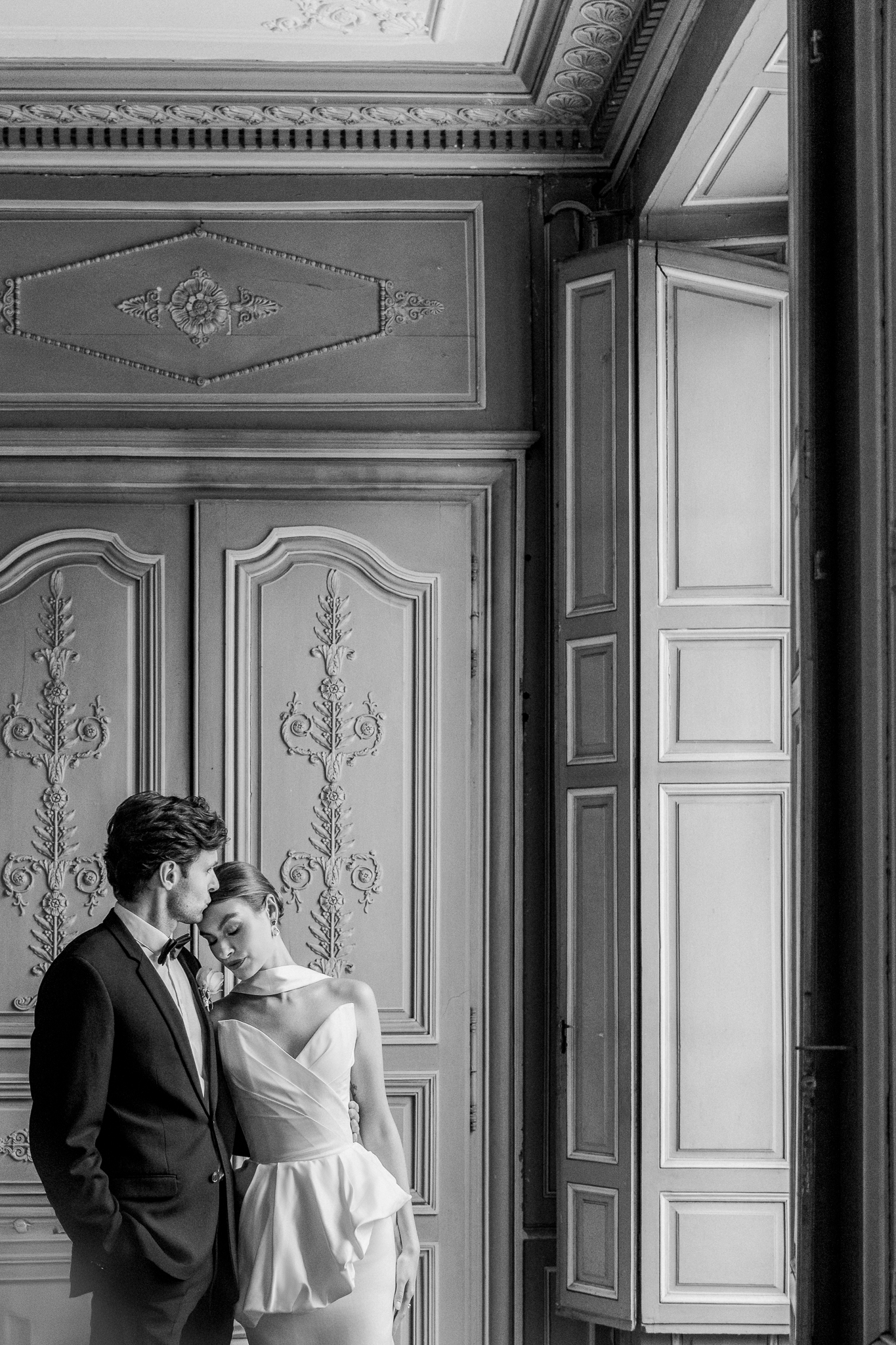 Intimate moment between bride and groom as they stand close together inside the grand halls of Château de Thauvenay in Sancerre, France.