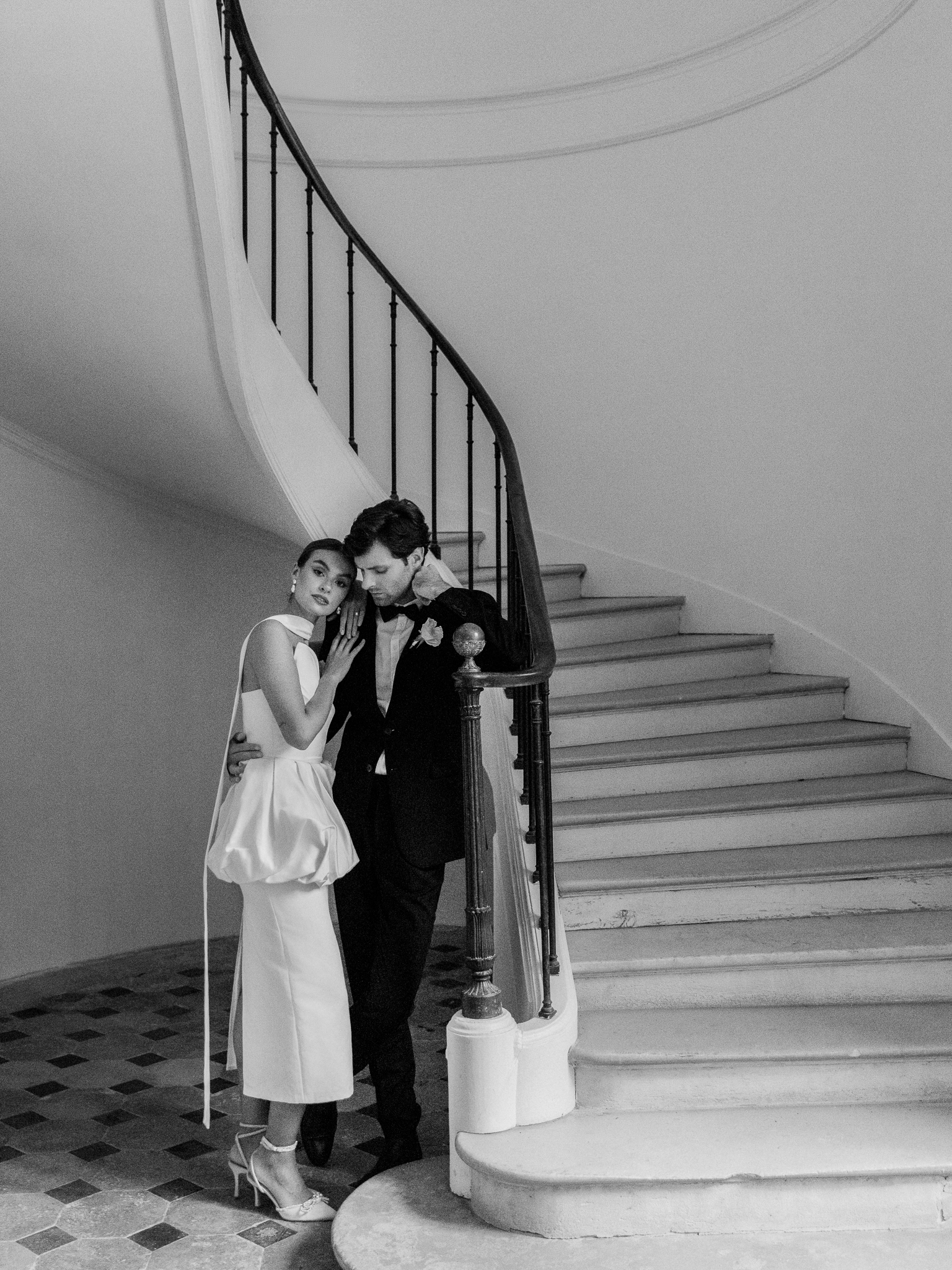 Black and white image of the couple embracing on the staircase of Château de Thauvenay, exuding timeless elegance and cinematic romance.